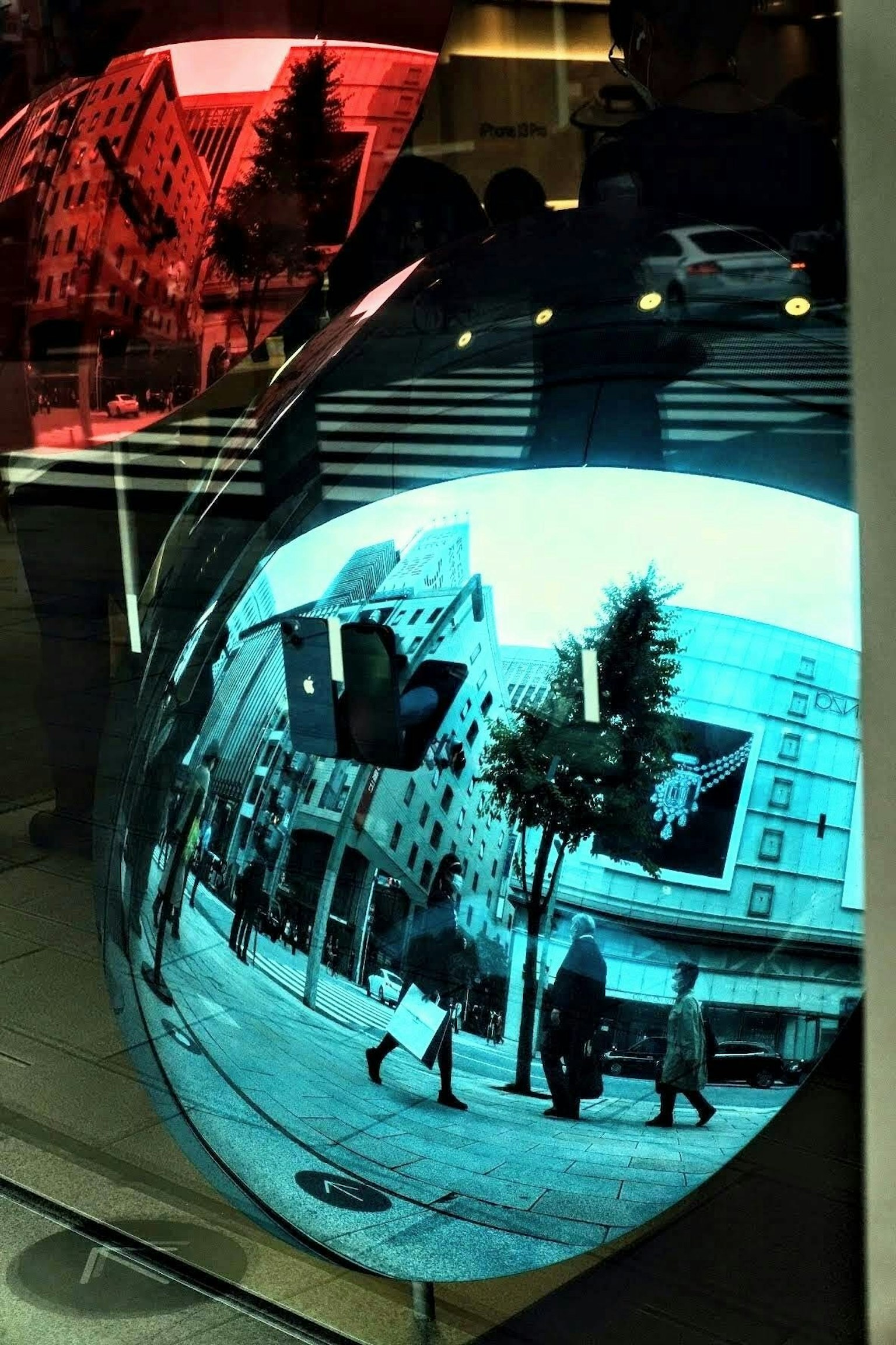 Stadtlandschaft und Fußgänger, reflektiert in einer blauen Oberfläche