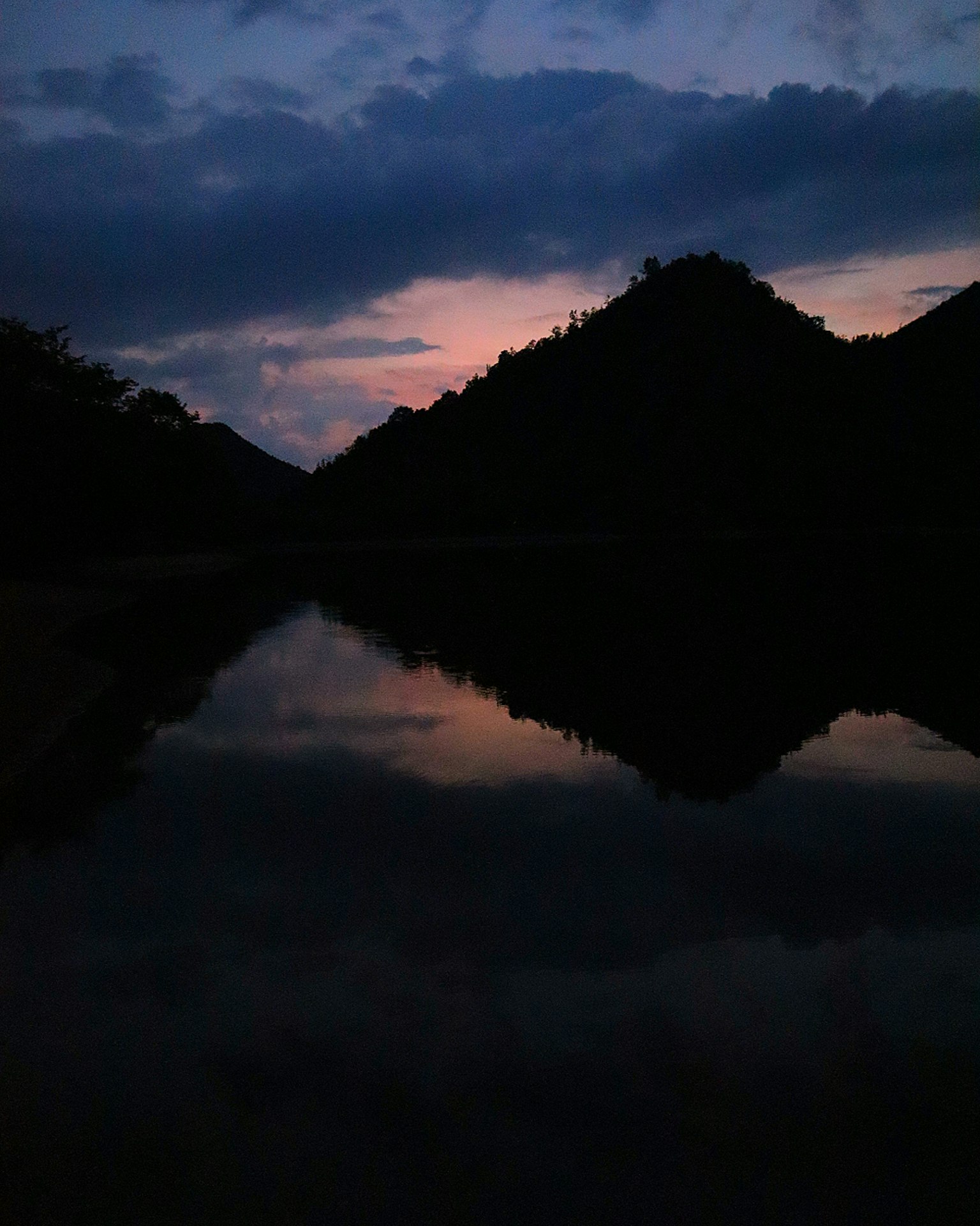 ทิวทัศน์ที่สวยงามของภูเขาในน้ำที่นิ่งสงบตอนพระอาทิตย์ตก