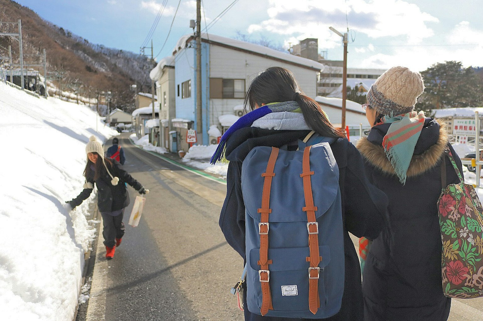 Menschen gehen auf einer verschneiten Straße mit Reisenden, die Rucksäcke tragen