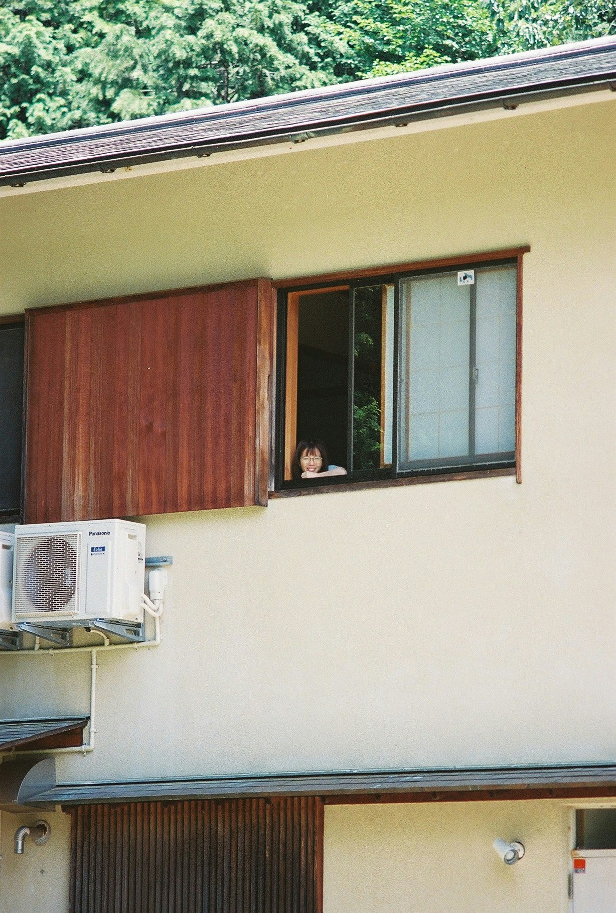 緑に囲まれた家の窓と室外機