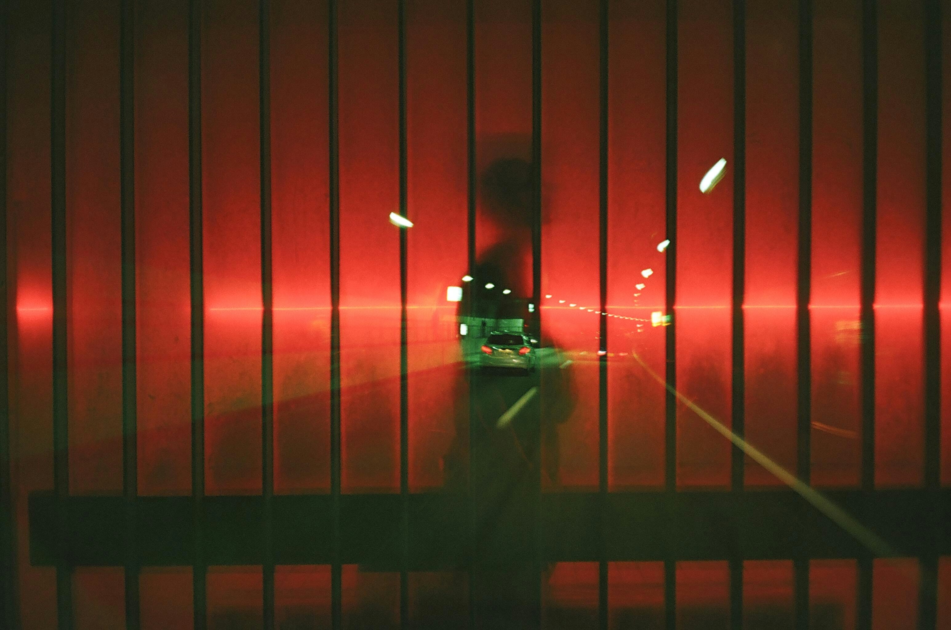 赤い街灯の下を走る車のある夜の道路