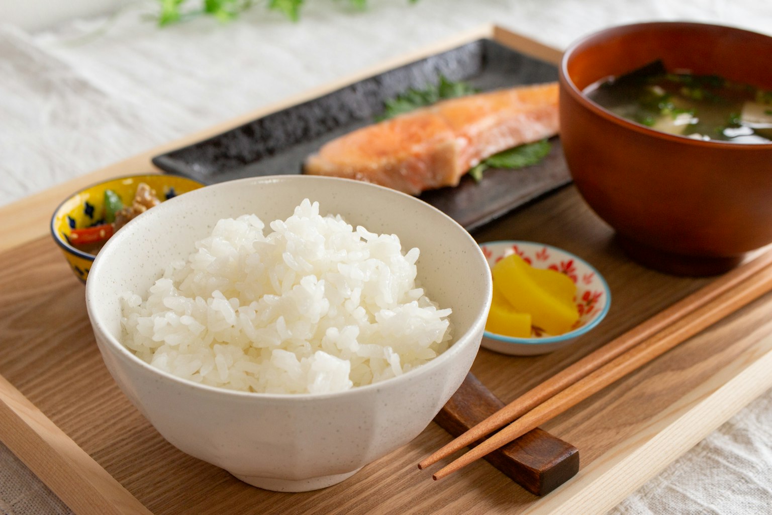 Ein Teller japanischer Küche mit weißem Reis, Miso-Suppe, gegrilltem Lachs und eingelegtem Gemüse