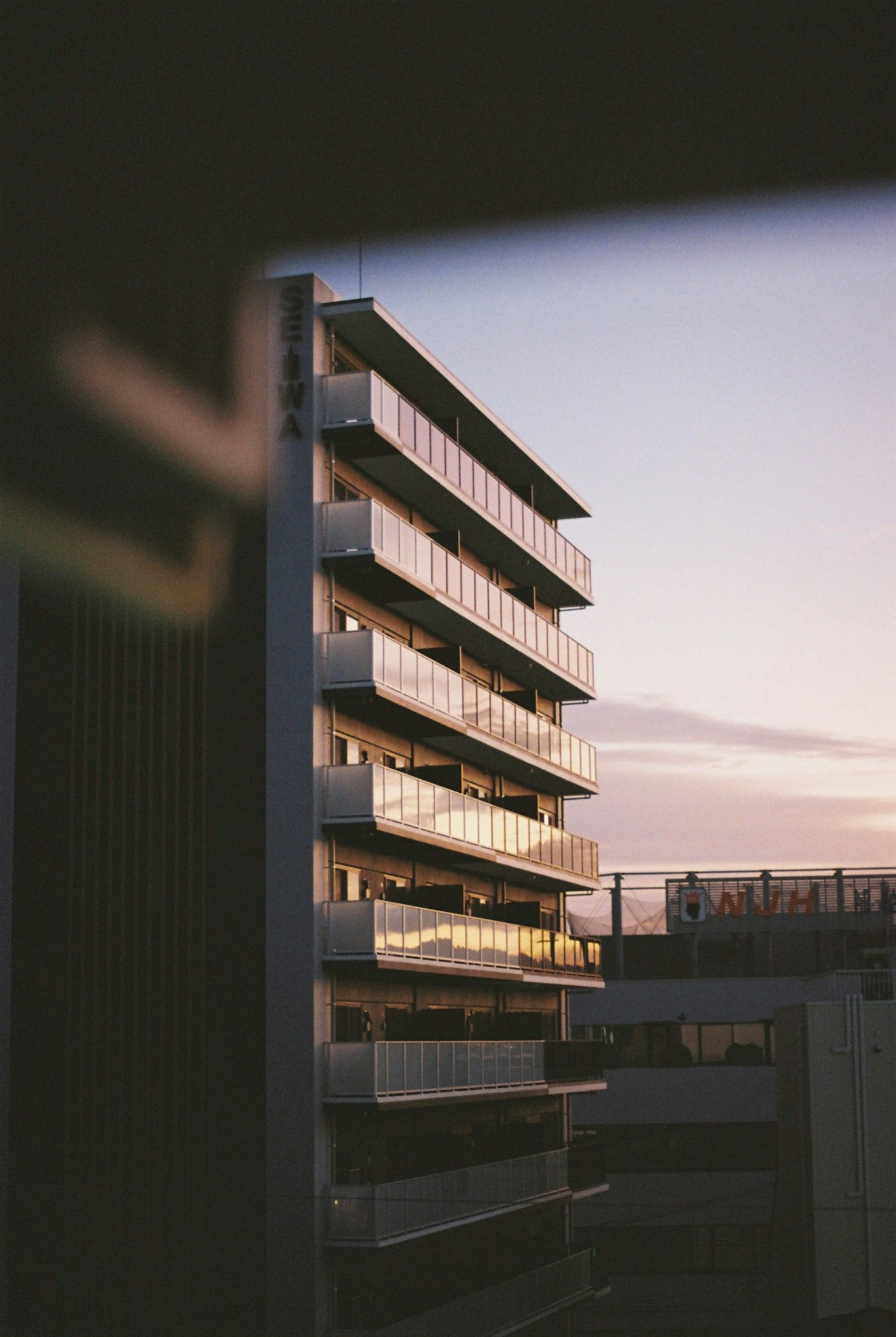 Exterior de un edificio moderno al anochecer visto a través de una ventana con reflejos