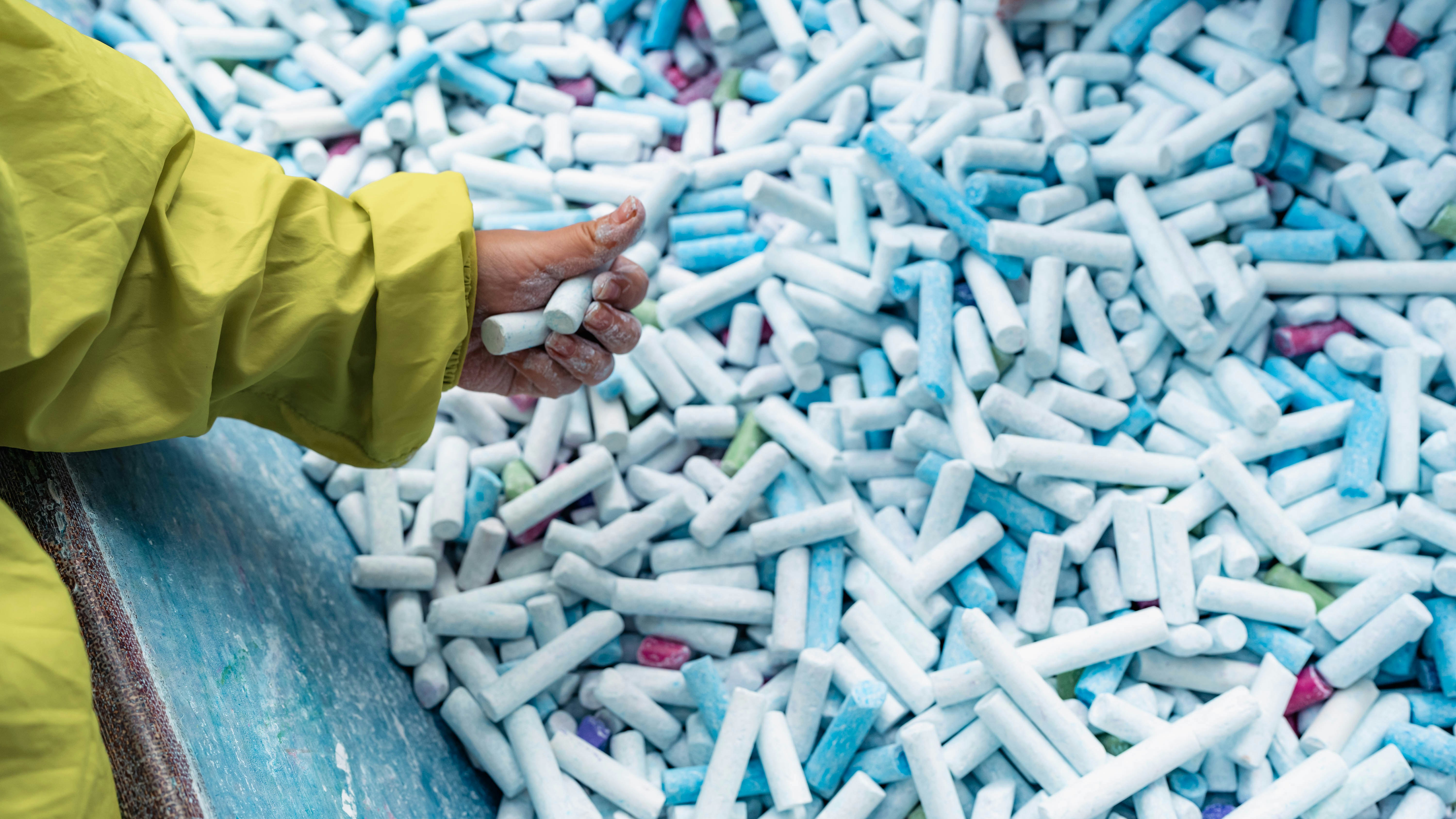 Une main touche un tas de gommes bleues dans un contexte d’apprentissage