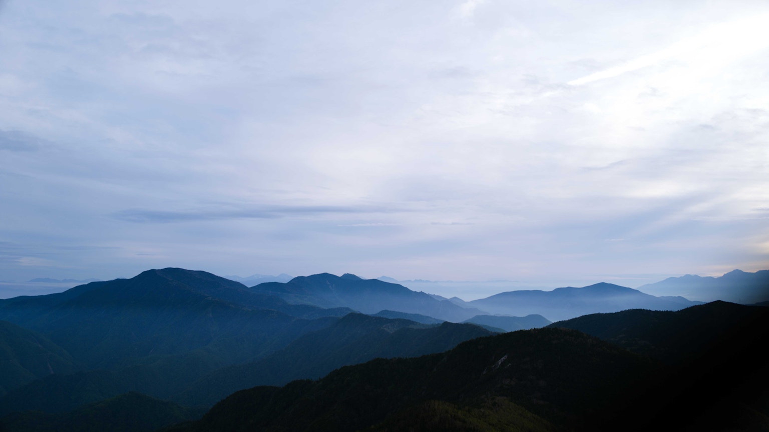 Montagnes bleues enveloppées de brume sous un ciel nuageux