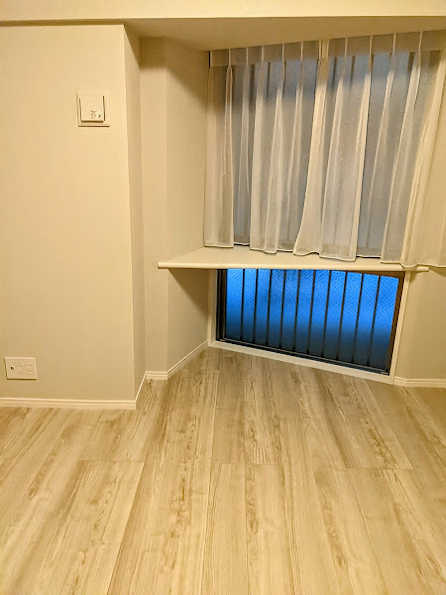 Heller Raumwinkel mit hellem Boden transparenten weißen Vorhängen und einem Fenster mit blauer Beleuchtung
