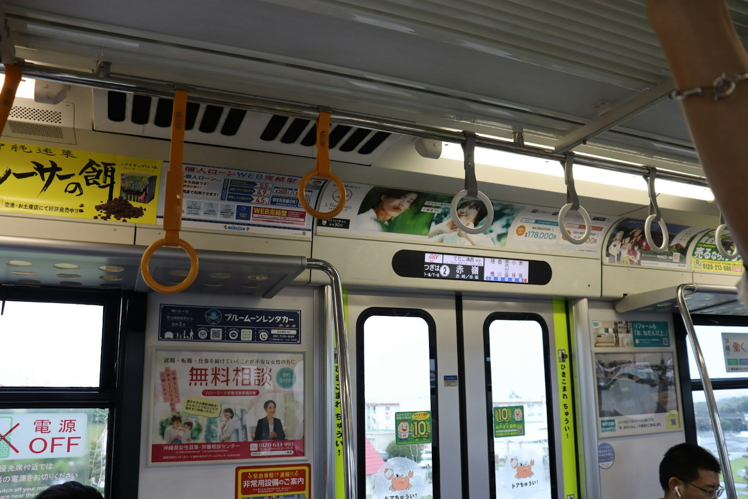 Interior de un tren con anuncios y agarraderas colgantes