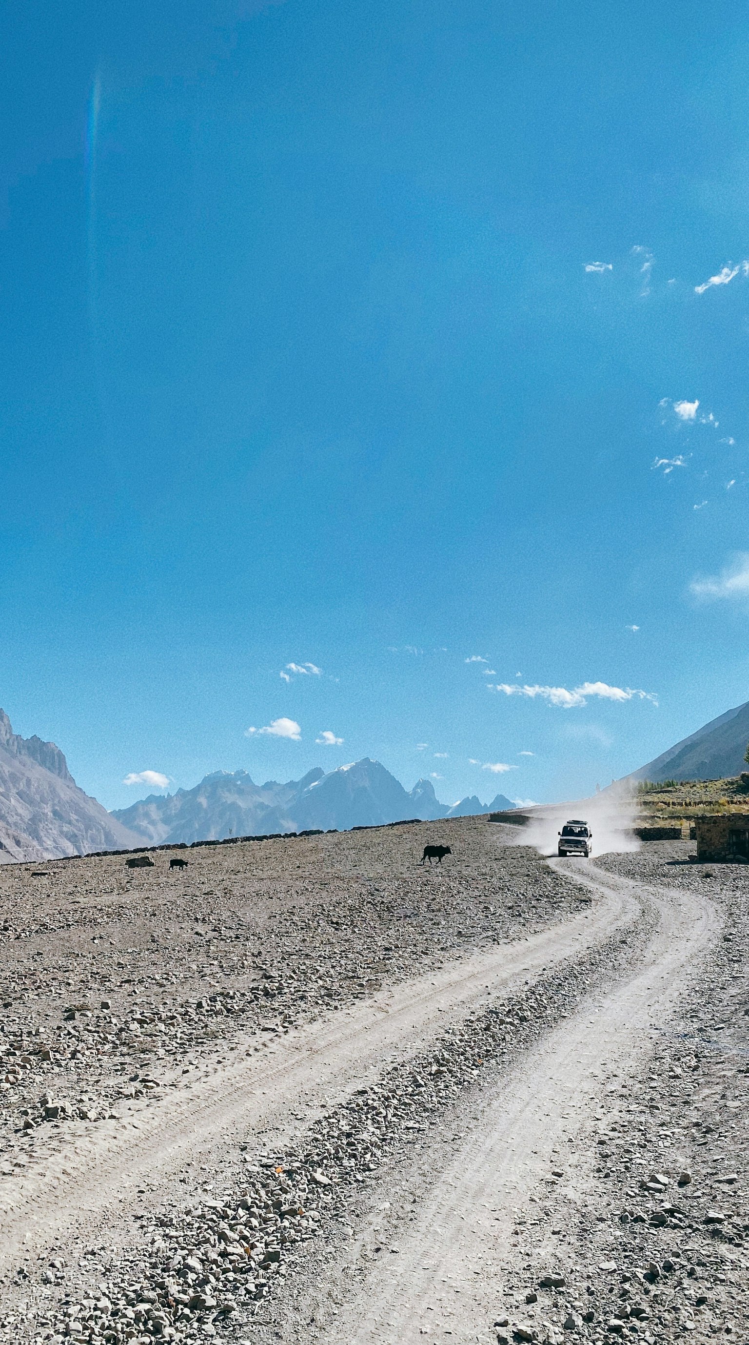 Gravel road leading towards mountains under a clear blue sky