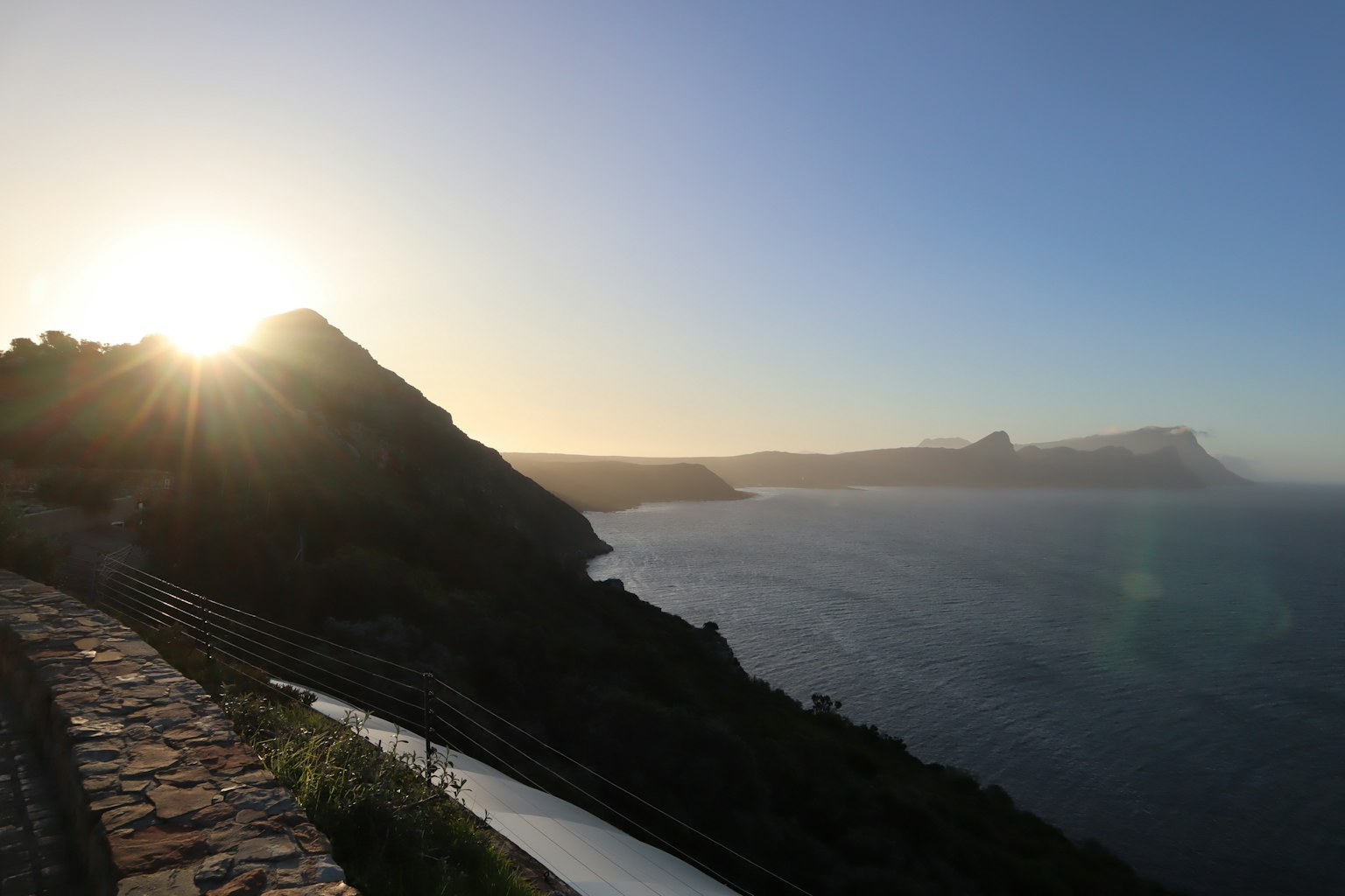 Vista costera escénica con montañas y atardecer sobre el océano