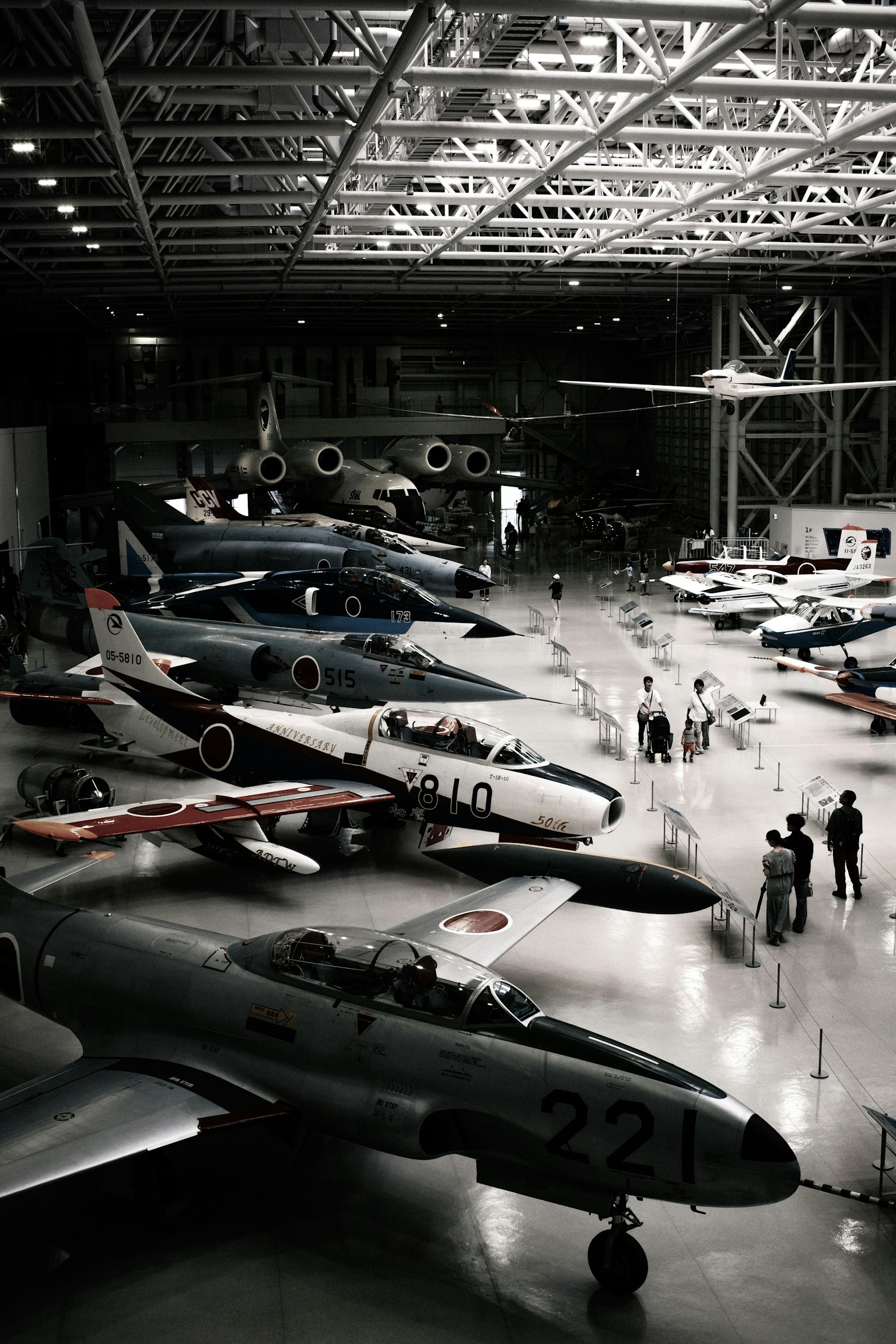 Interno di un museo dell'aviazione con vari caccia e aerei con visitatori in esplorazione