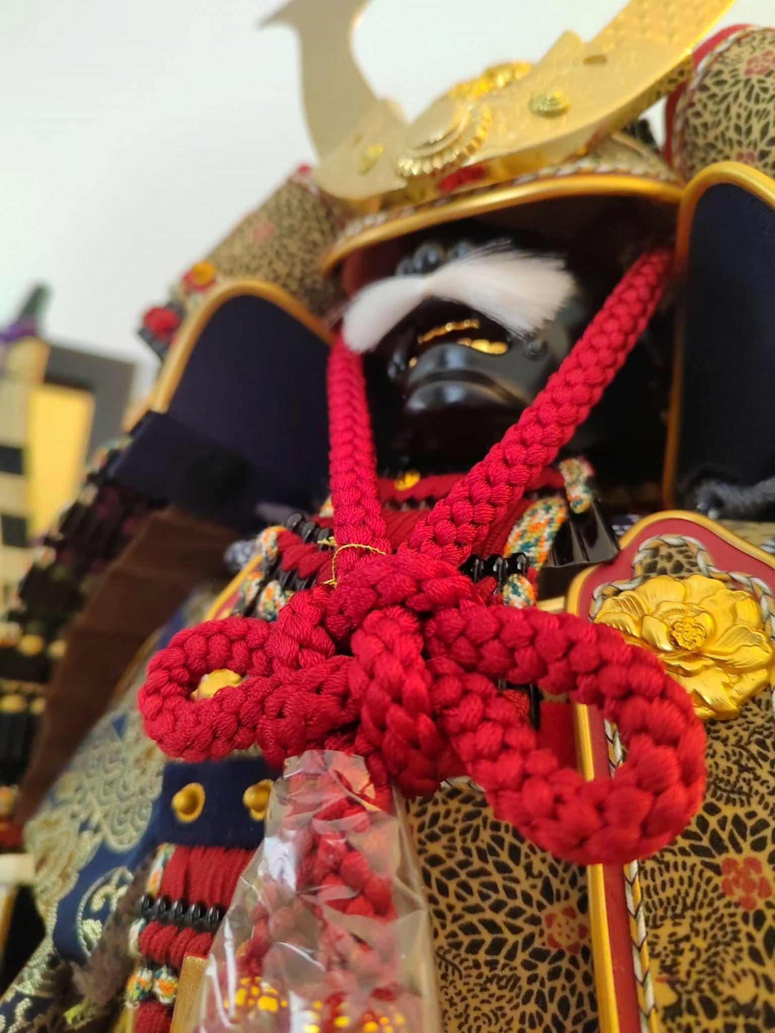 Gros plan d'une poupée samouraï japonaise portant une armure ornée avec un nœud décoratif rouge distinctif