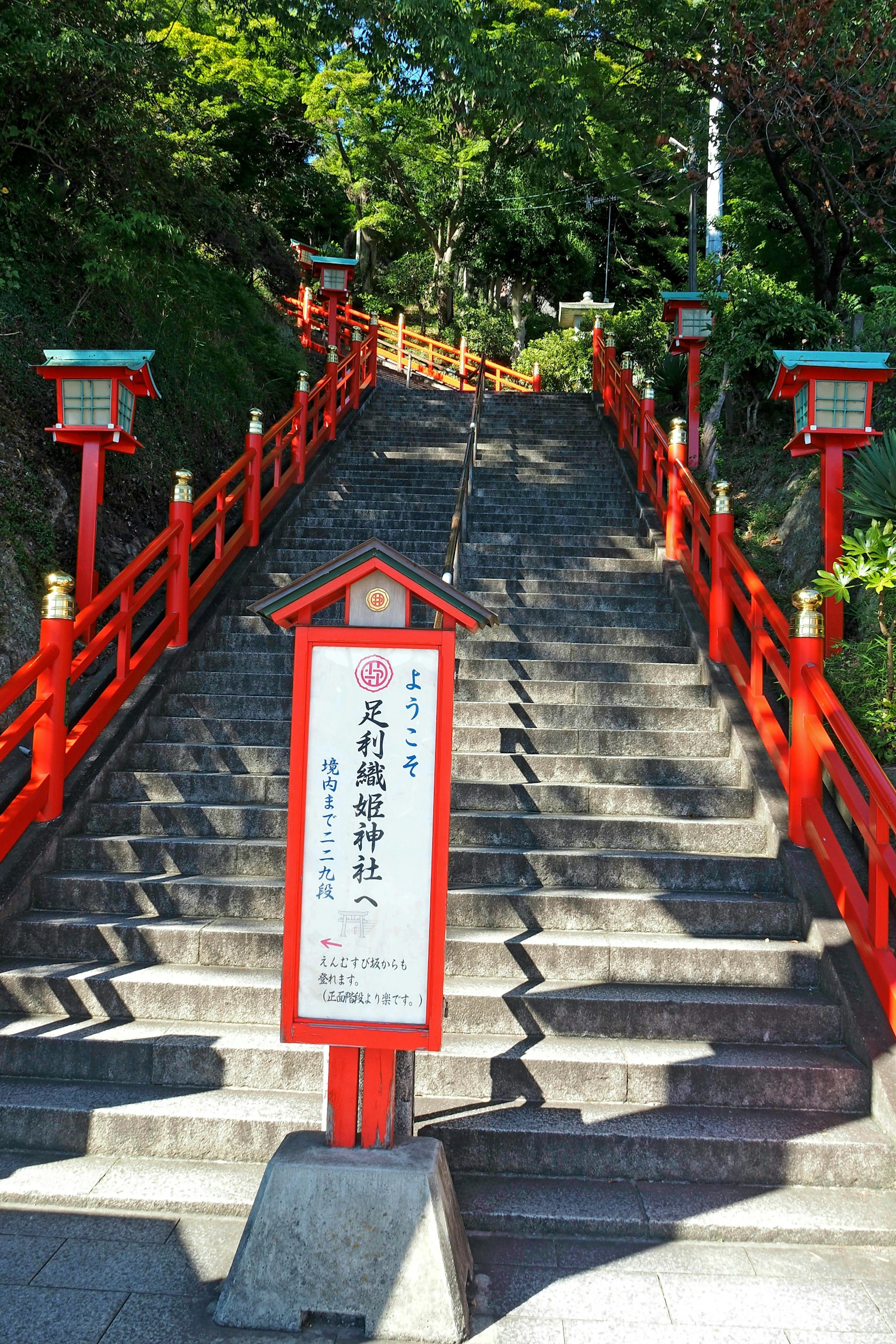 Stairs leading to a shrine with red railings and a sign