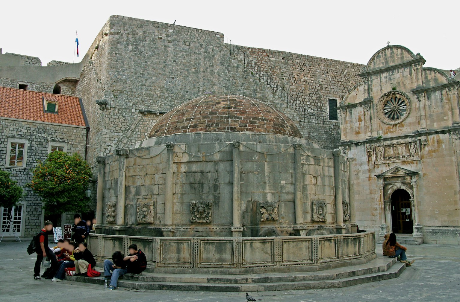 Fontaine historique à Dubrovnik avec des personnes assises autour