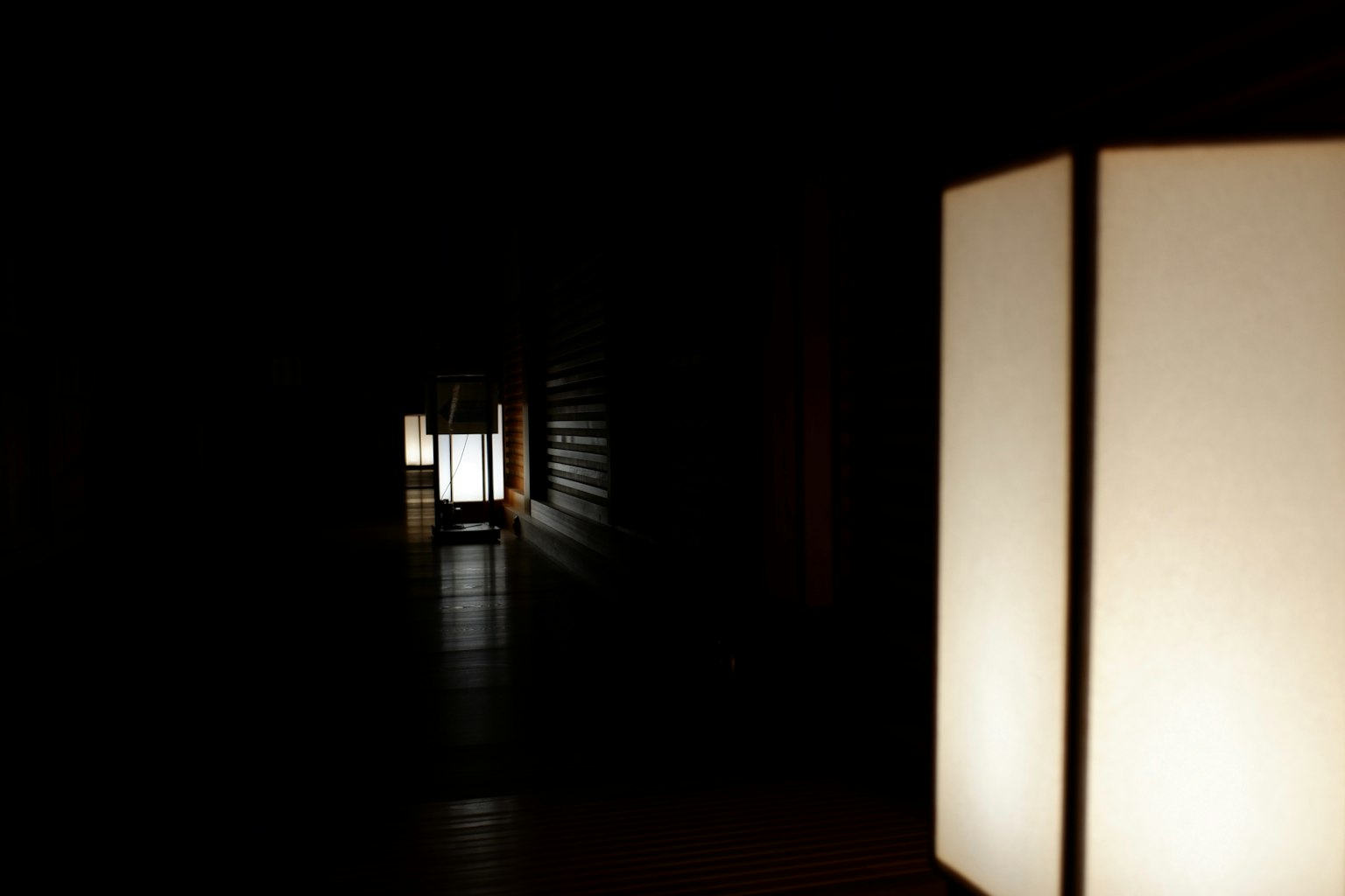 Un couloir sombre avec des lanternes blanches créant une ambiance sereine