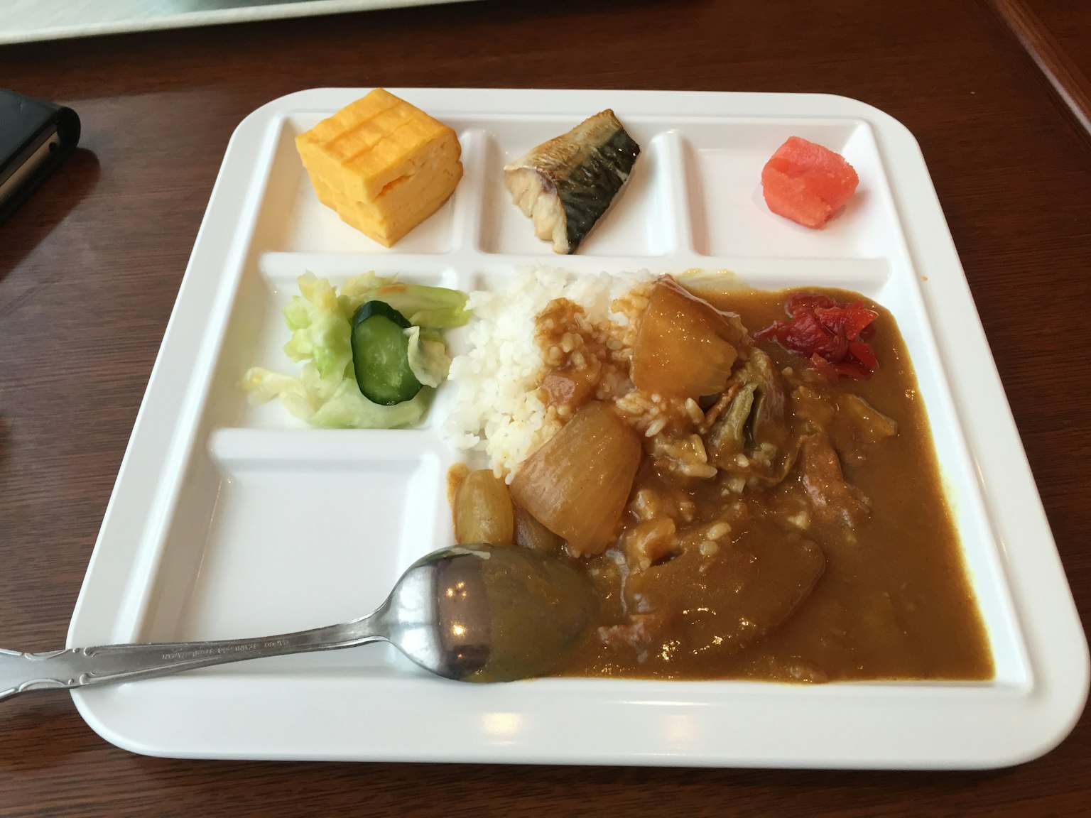 Arroz al curry servido en un plato blanco con varios acompañamientos