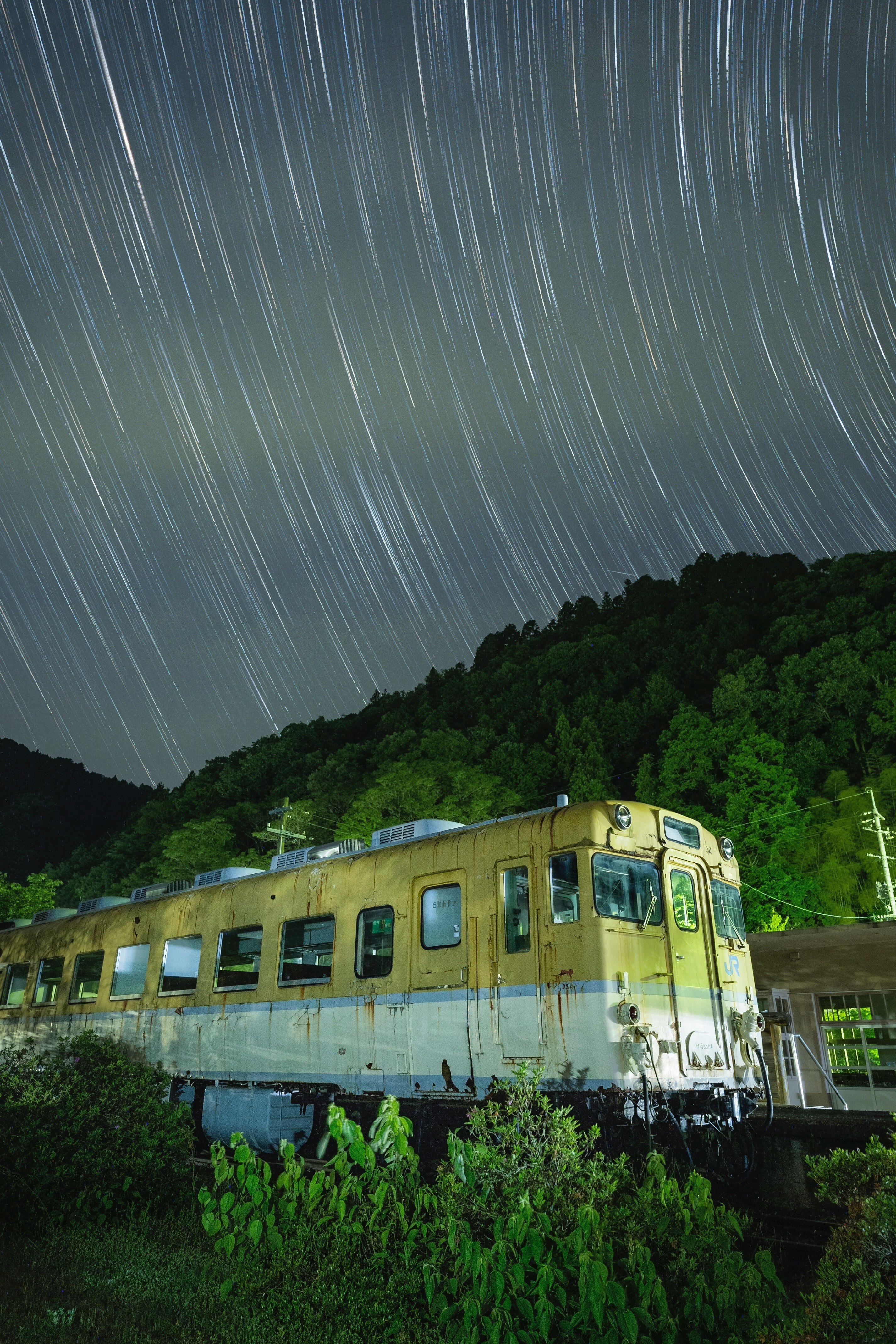 Un tren KiHa 58 detenido bajo un cielo nocturno en time-lapse de estrellas