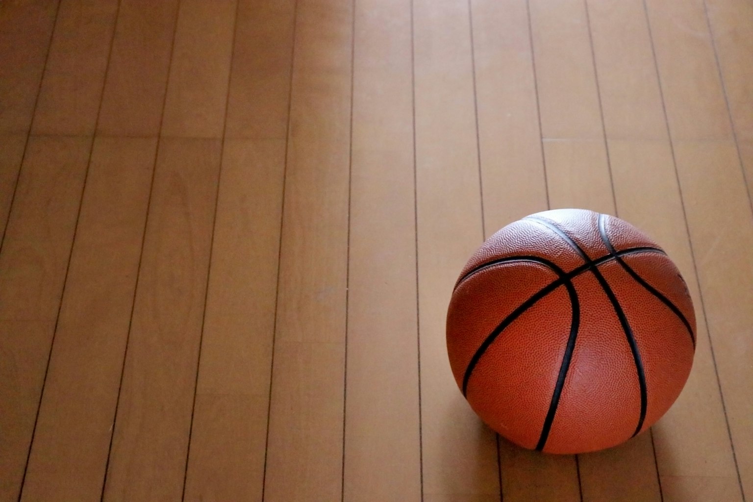 Sebuah bola basket di atas lantai kayu dalam komposisi sederhana