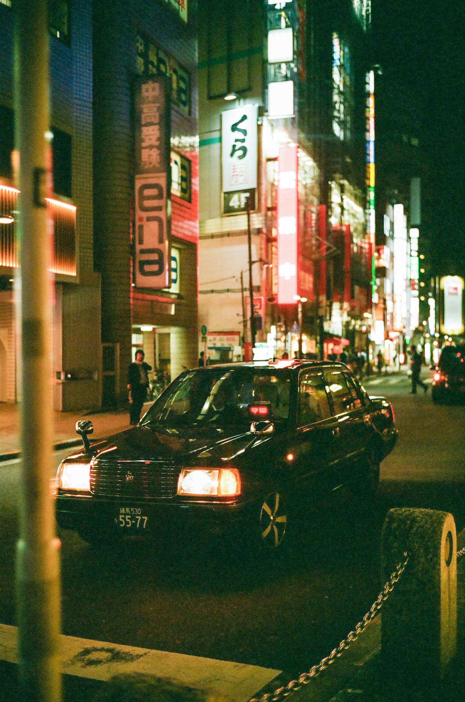 Schwarzes Taxi fährt durch die neonbeleuchteten Straßen Tokios bei Nacht