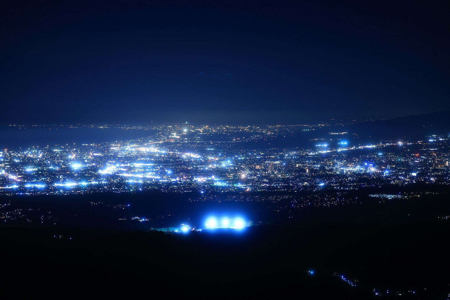 Pemandangan malam kota dengan lampu terang dan sorot biru