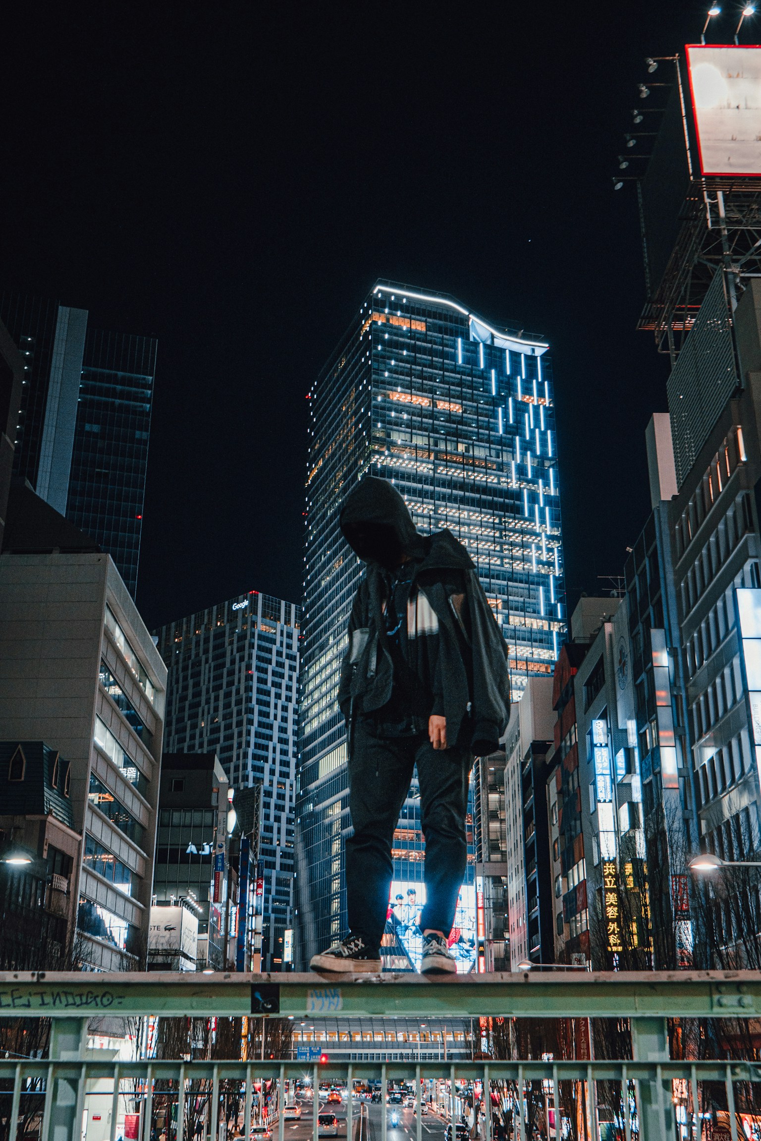 Eine mit Kapuze bekleidete Person steht vor einer Stadt bei Nacht