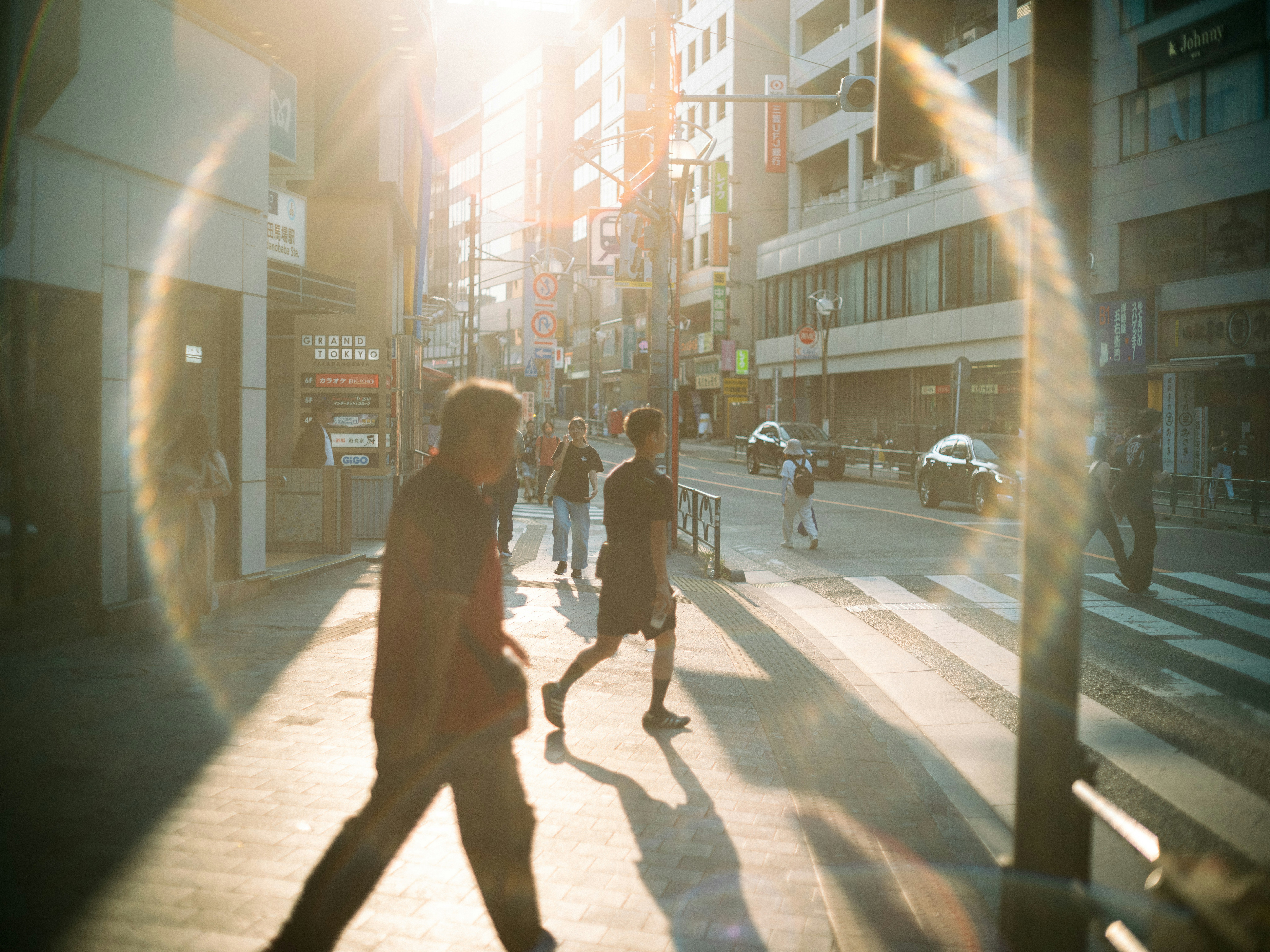 夕方の光が差し込む街の歩道と人々