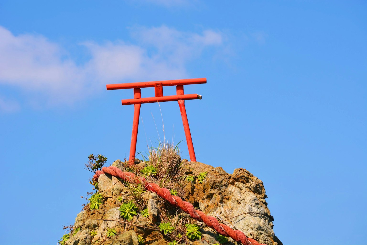 Roter Torii auf einem Felsen vor blauem Himmel