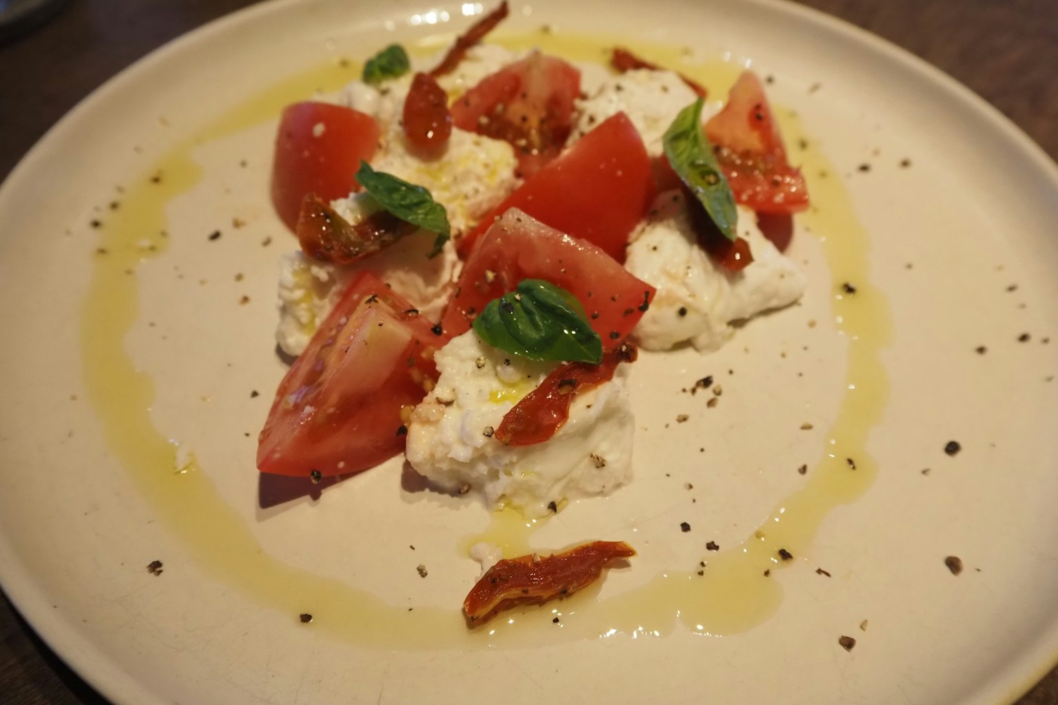 Salat mit Tomaten und Mozzarella, garniert mit Basilikum und Olivenöl
