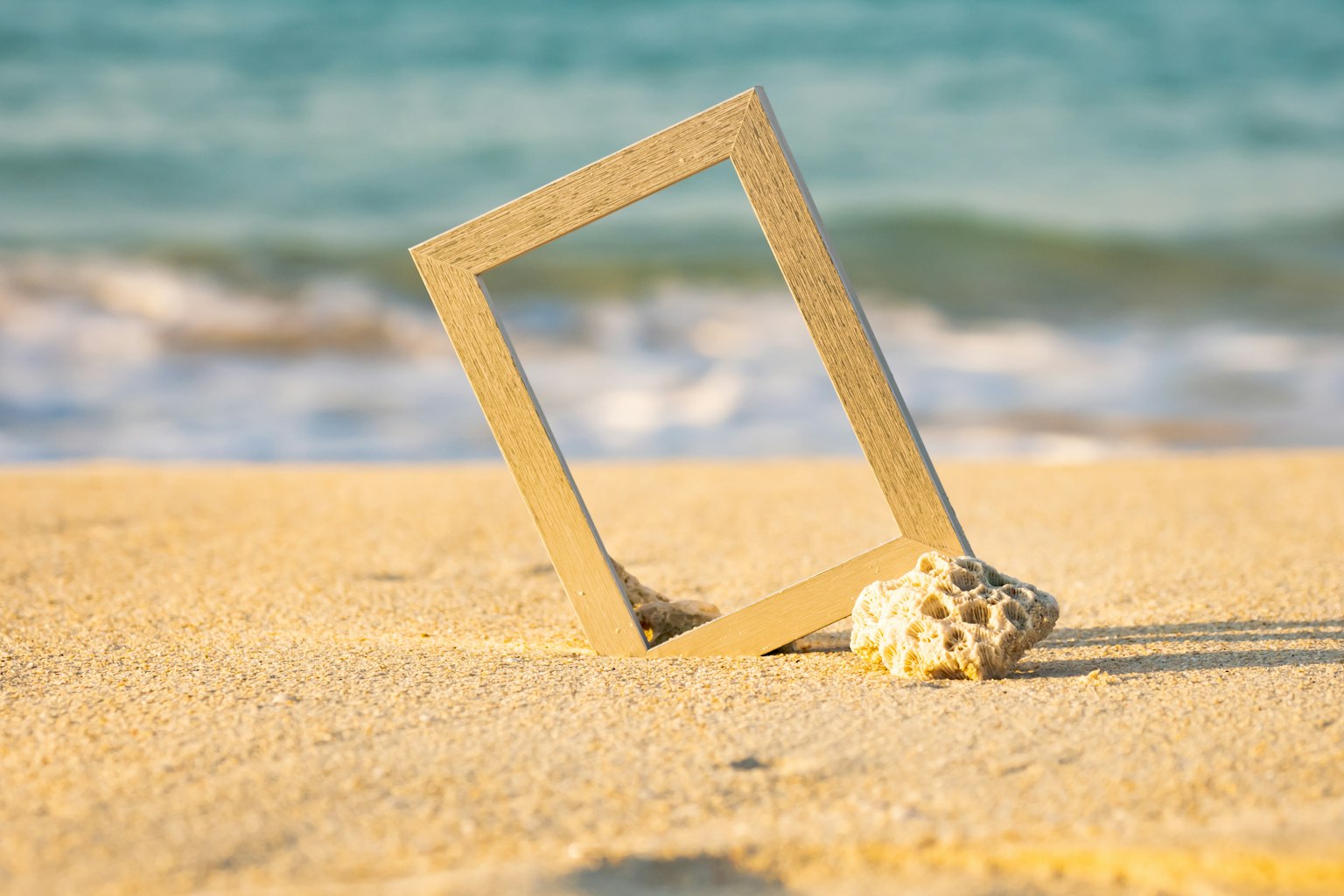 Cadre doré reposant sur le sable avec un coquillage sur la plage