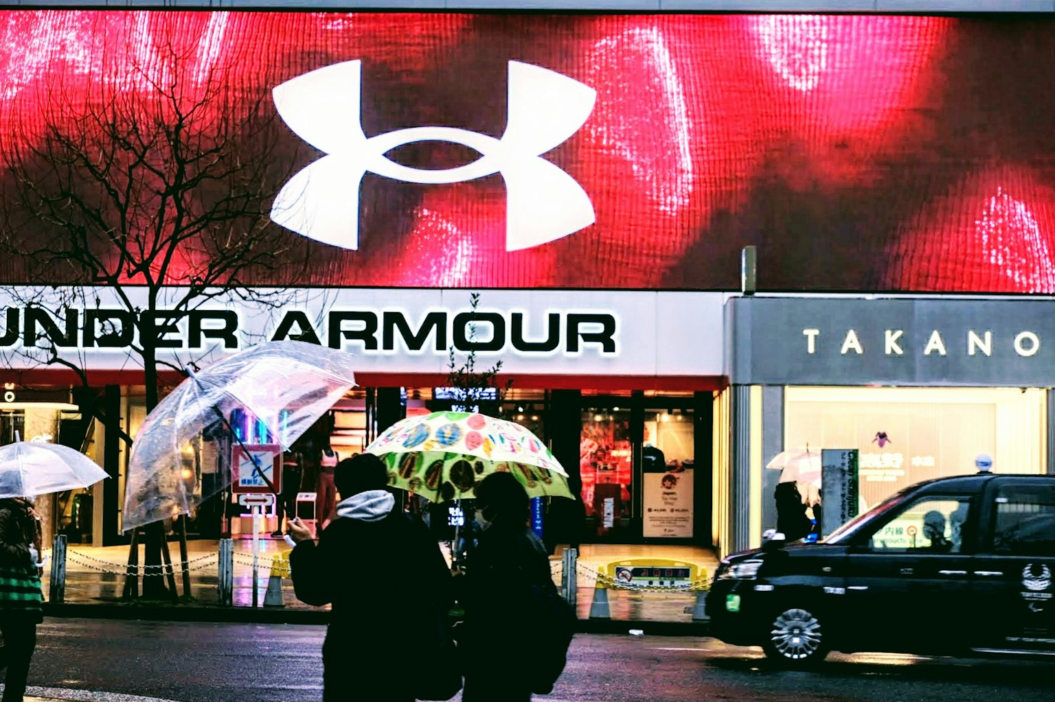 โลโก้ Under Armour ที่แสดงอย่างเด่นชัดพร้อมผู้คนที่ถือร่ม