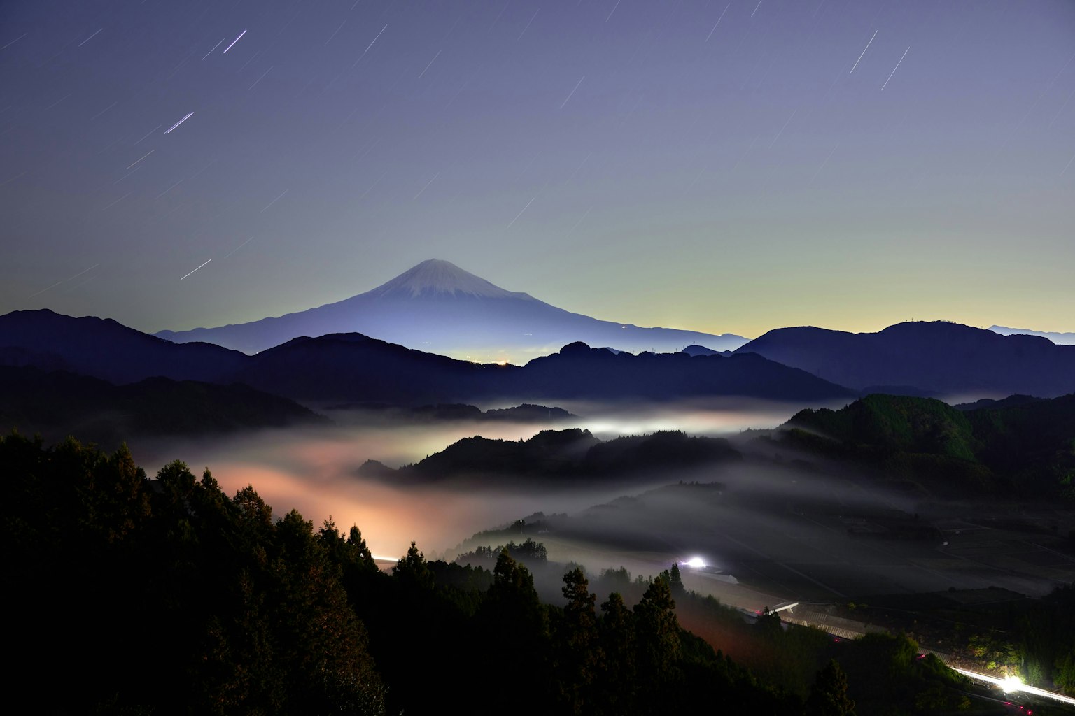 Magnifica vista notturna del monte Fuji circondato da montagne nebbiose