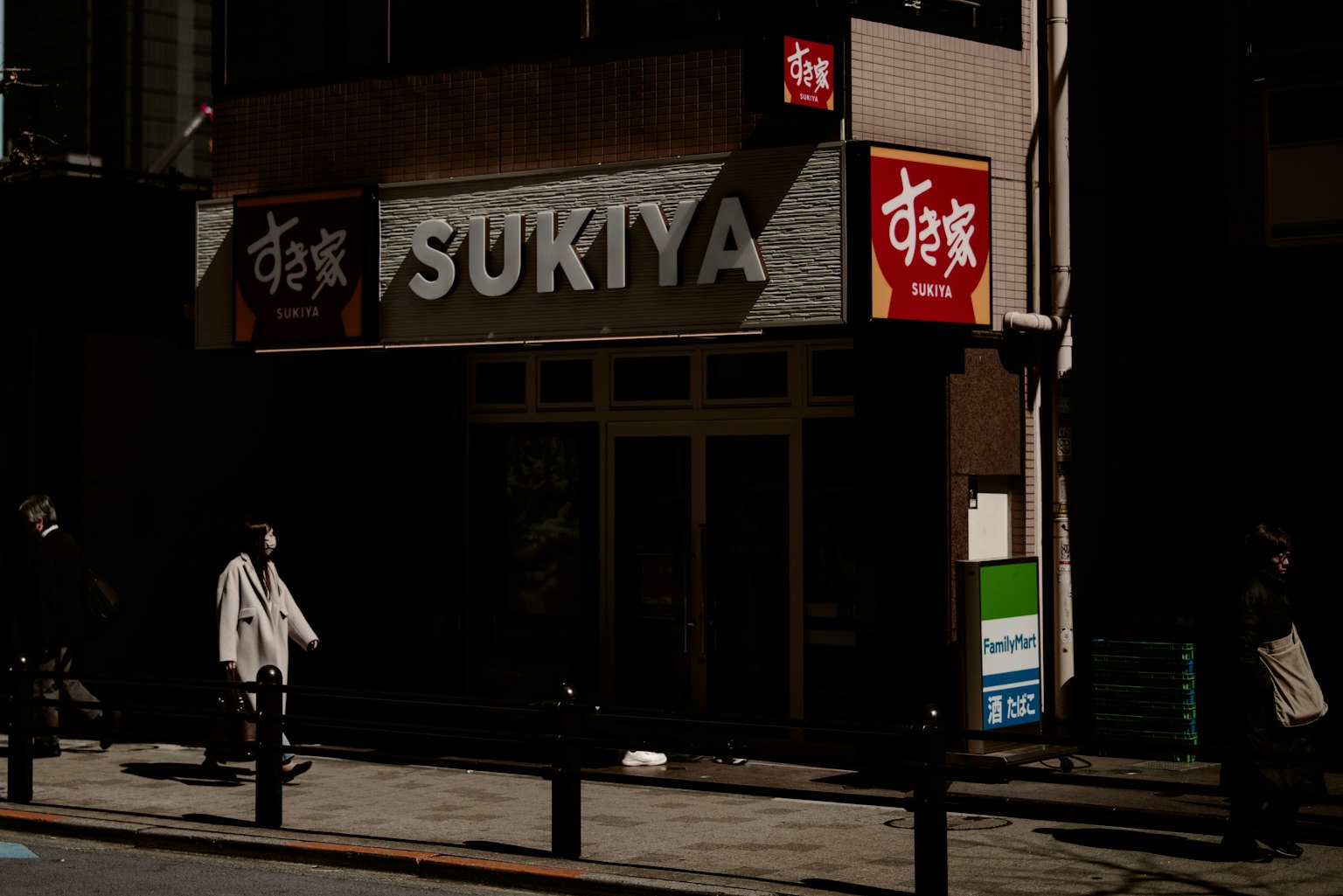 Insegna del ristorante Sukiya in una strada poco illuminata con pedoni