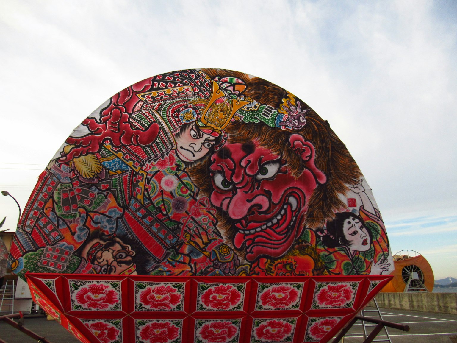 Colorful traditional Japanese float design featuring a demon face and a samurai