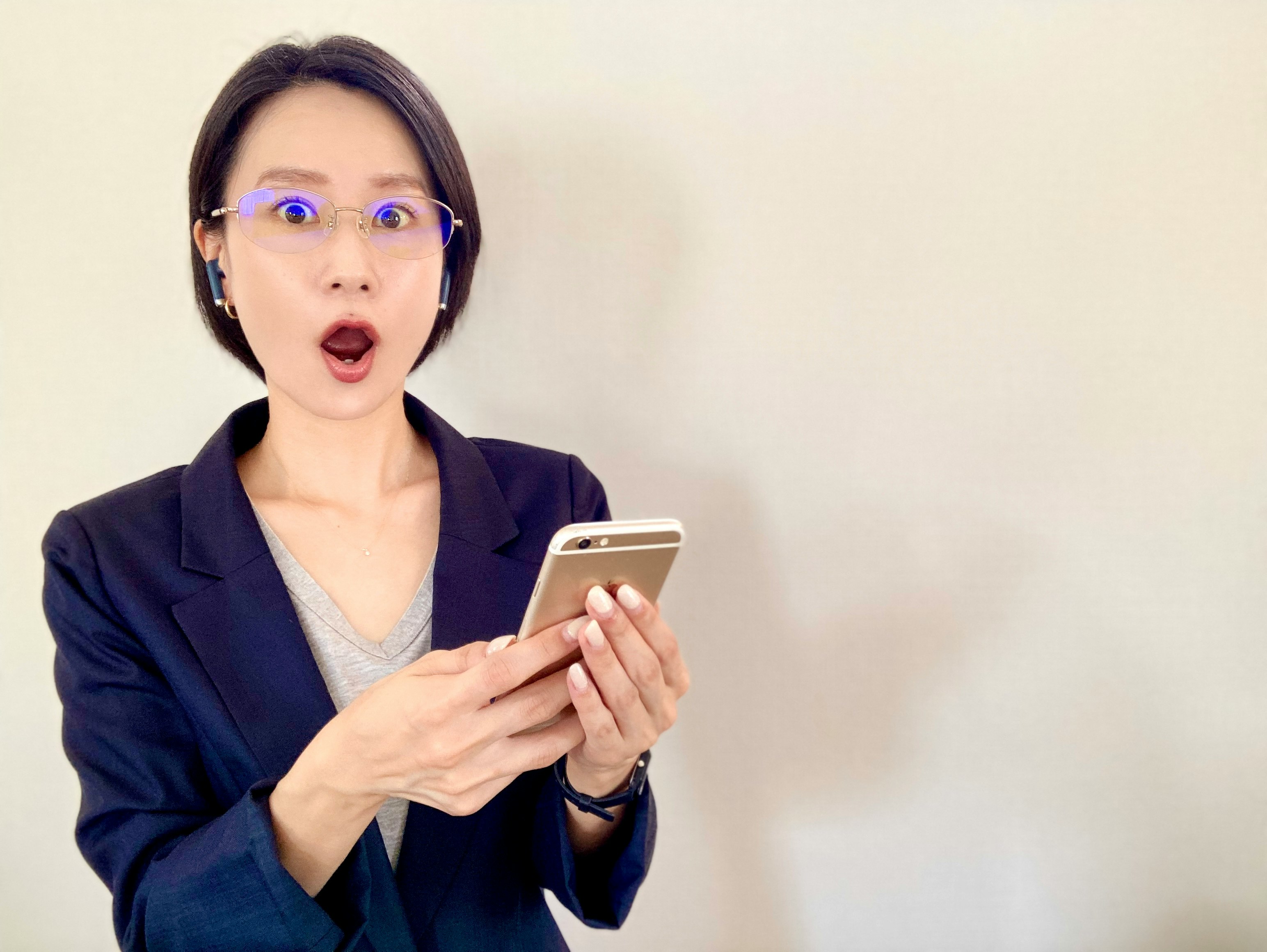 Wanita memegang smartphone dengan ekspresi terkejut