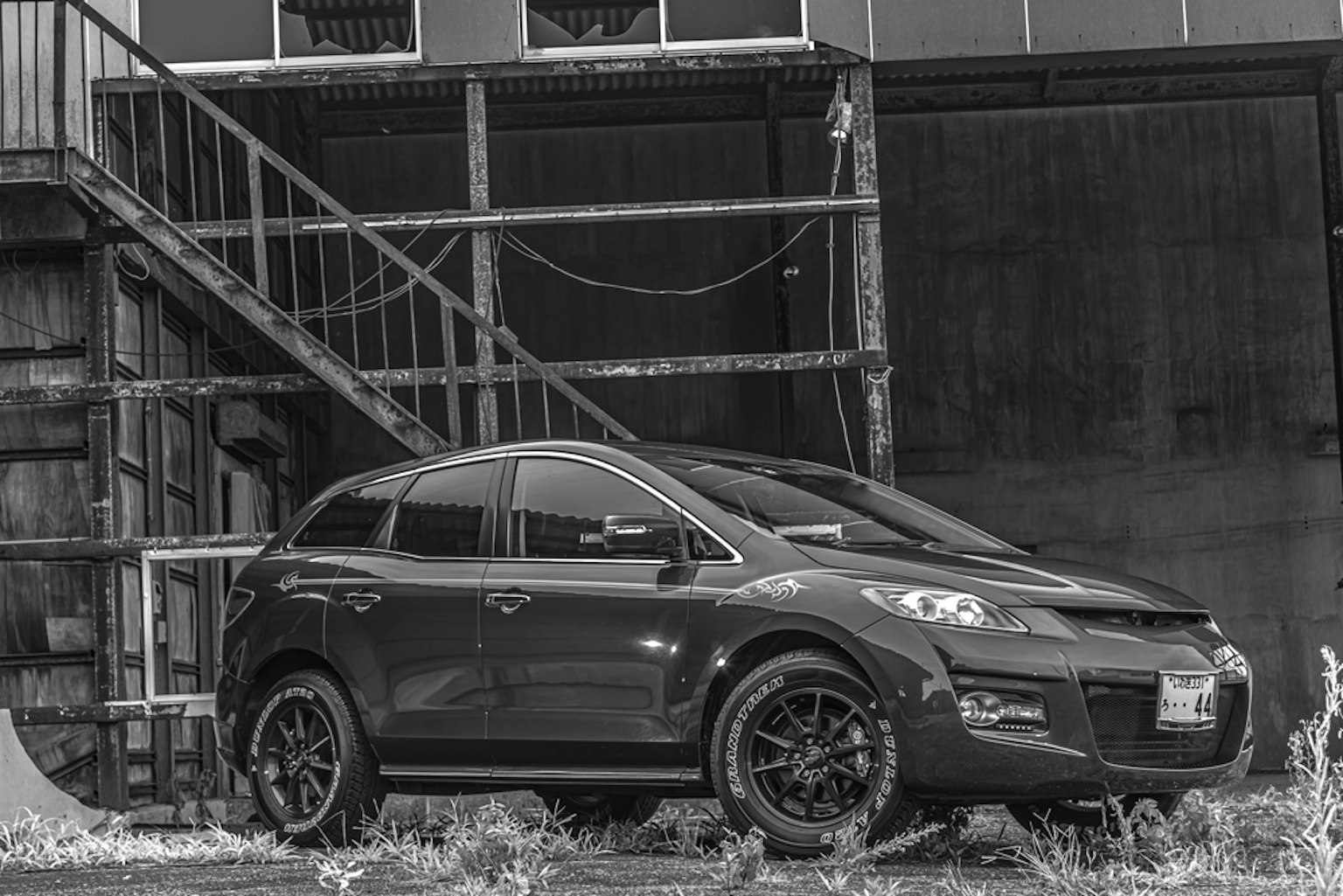 SUV negro aparcado frente a un fondo industrial antiguo