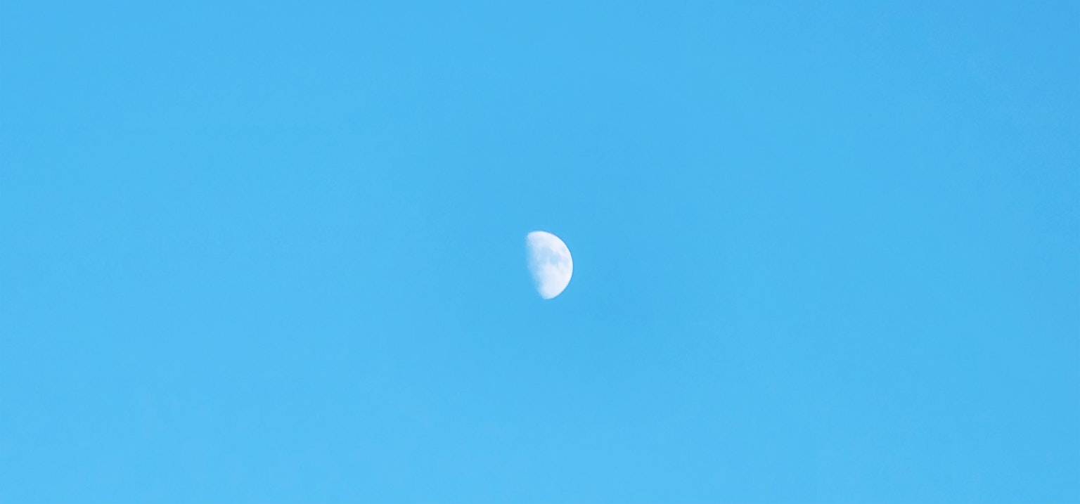Half moon against a clear blue sky