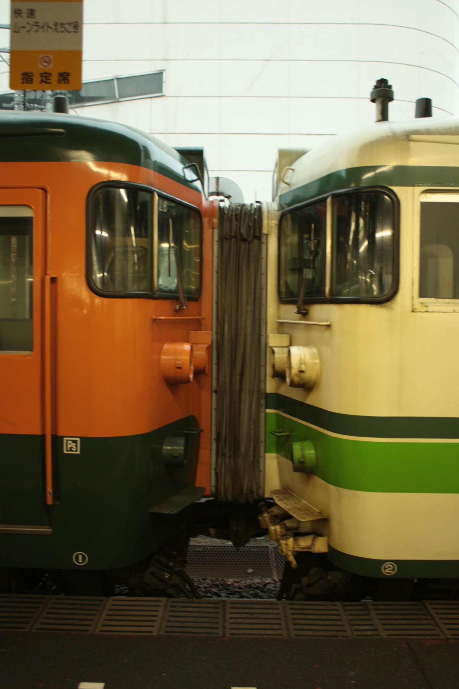 Trenes naranja y verde uno al lado del otro en una estación