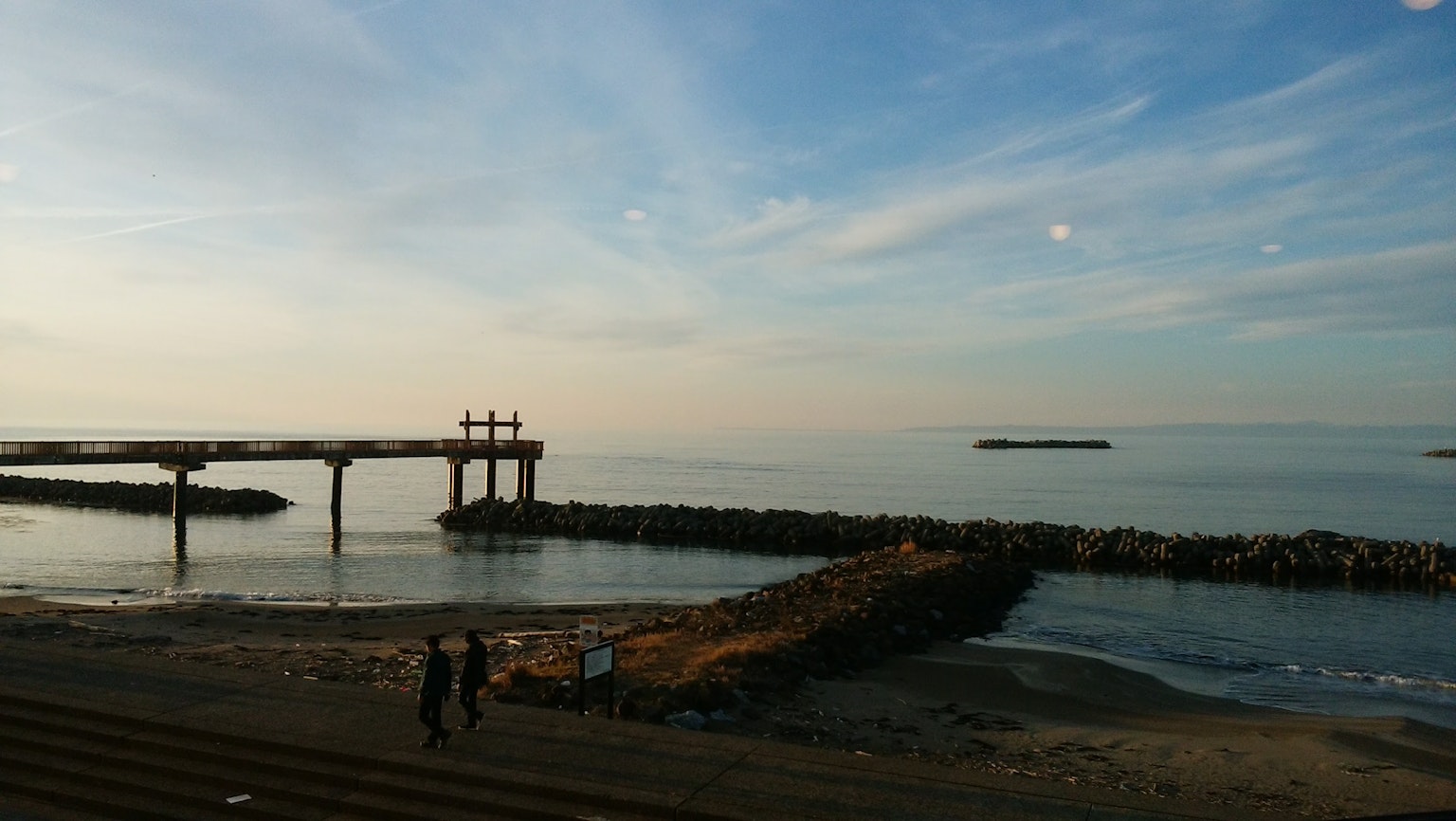 平靜的海洋和天空景觀，有一個碼頭和遠處的島嶼