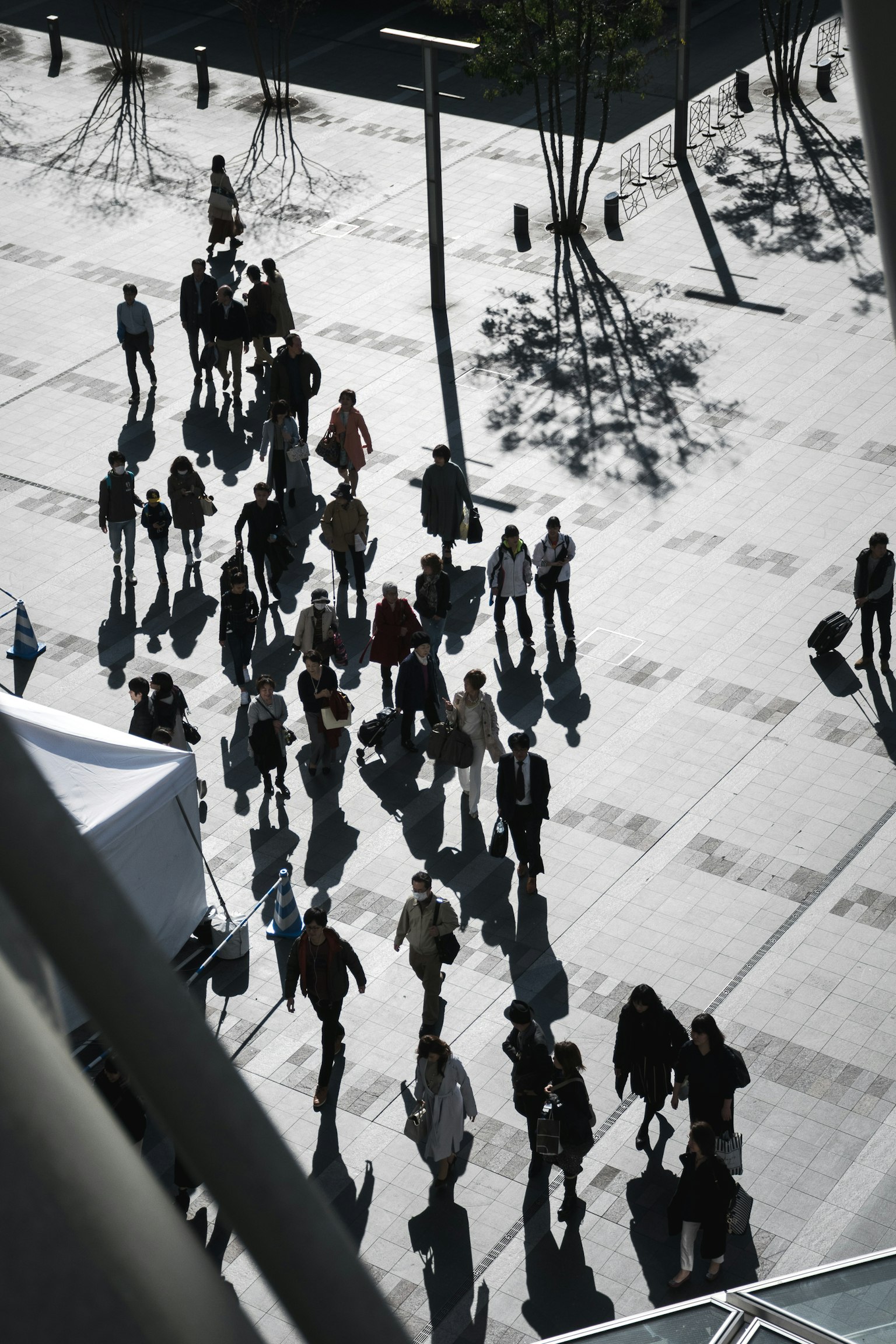 Luftaufnahme von Menschen, die mit Schatten auf einem Platz gehen