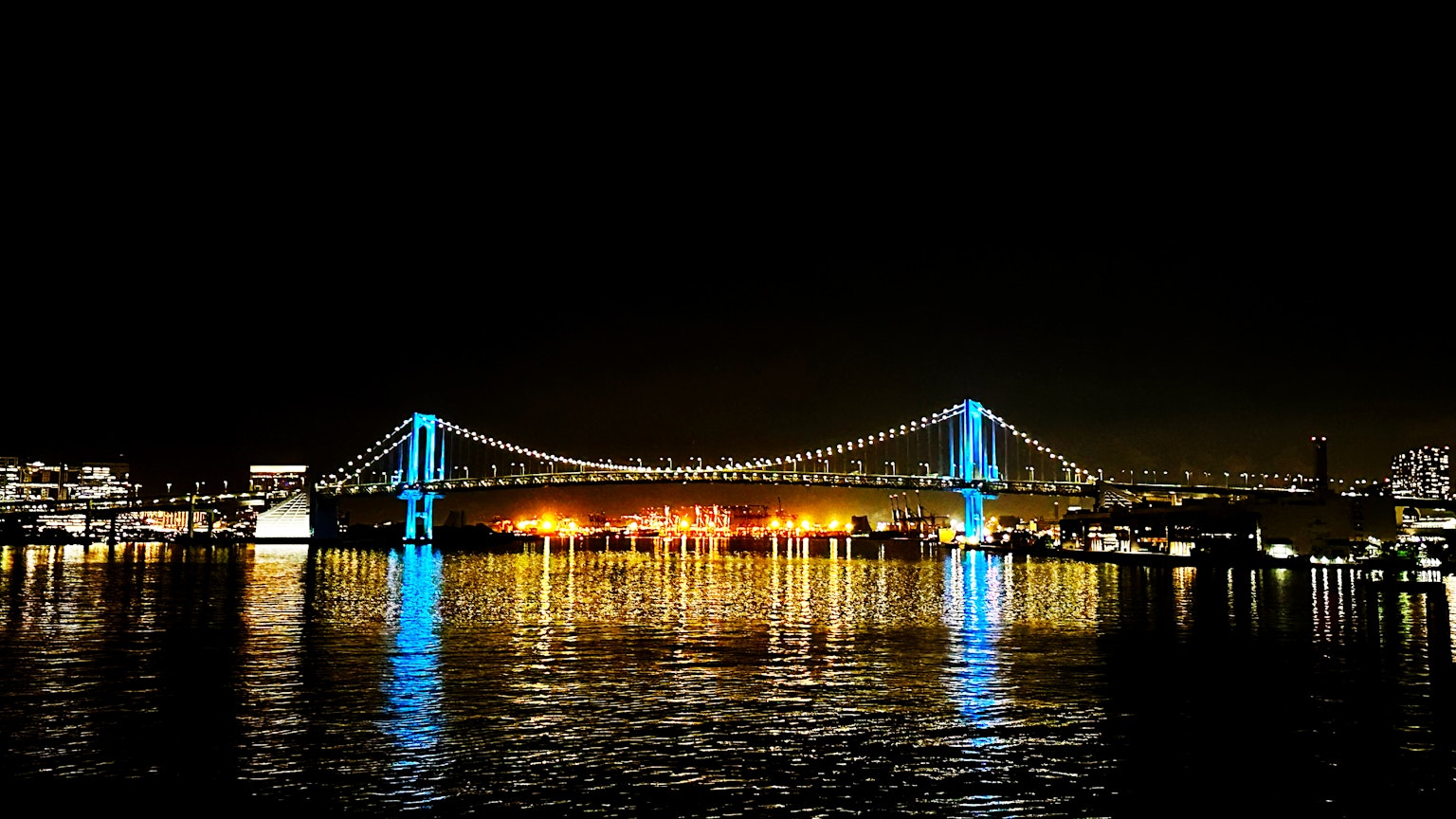 Rainbow Bridge nachts beleuchtet mit blauen und orangefarbenen Lichtern