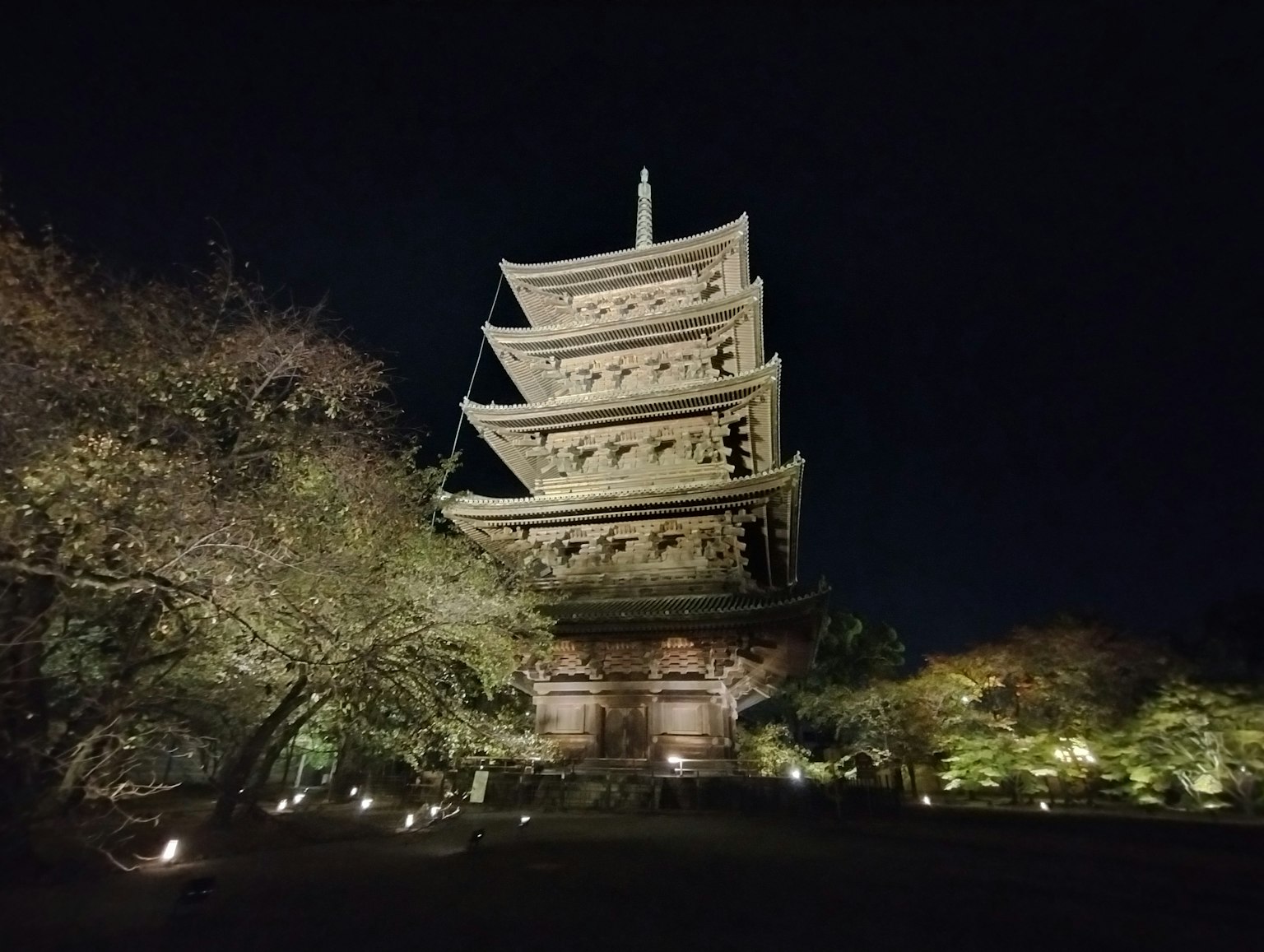 Illuminated pagoda at night with surrounding trees