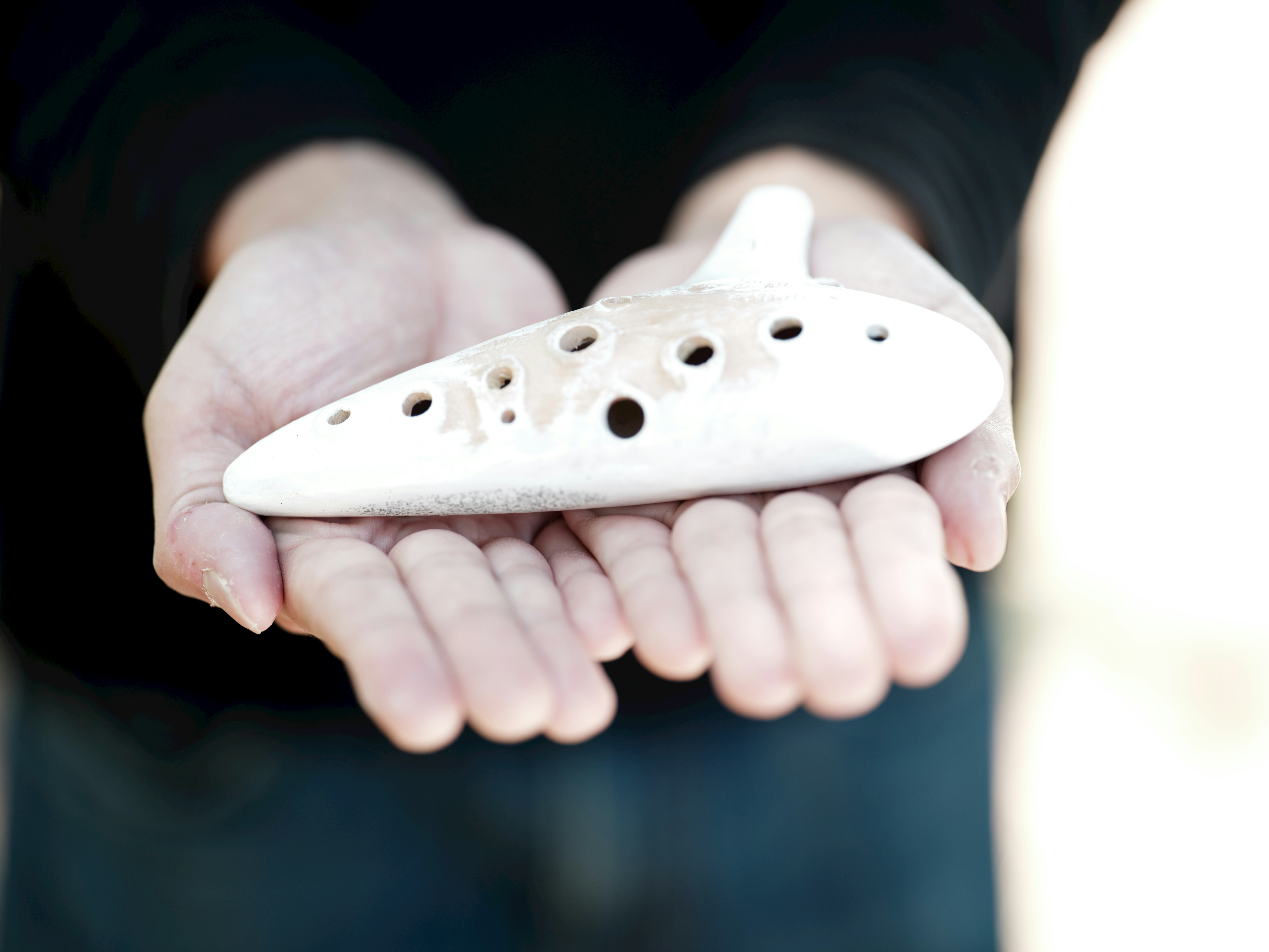 ocarina in ceramica bianca tenuta in mano