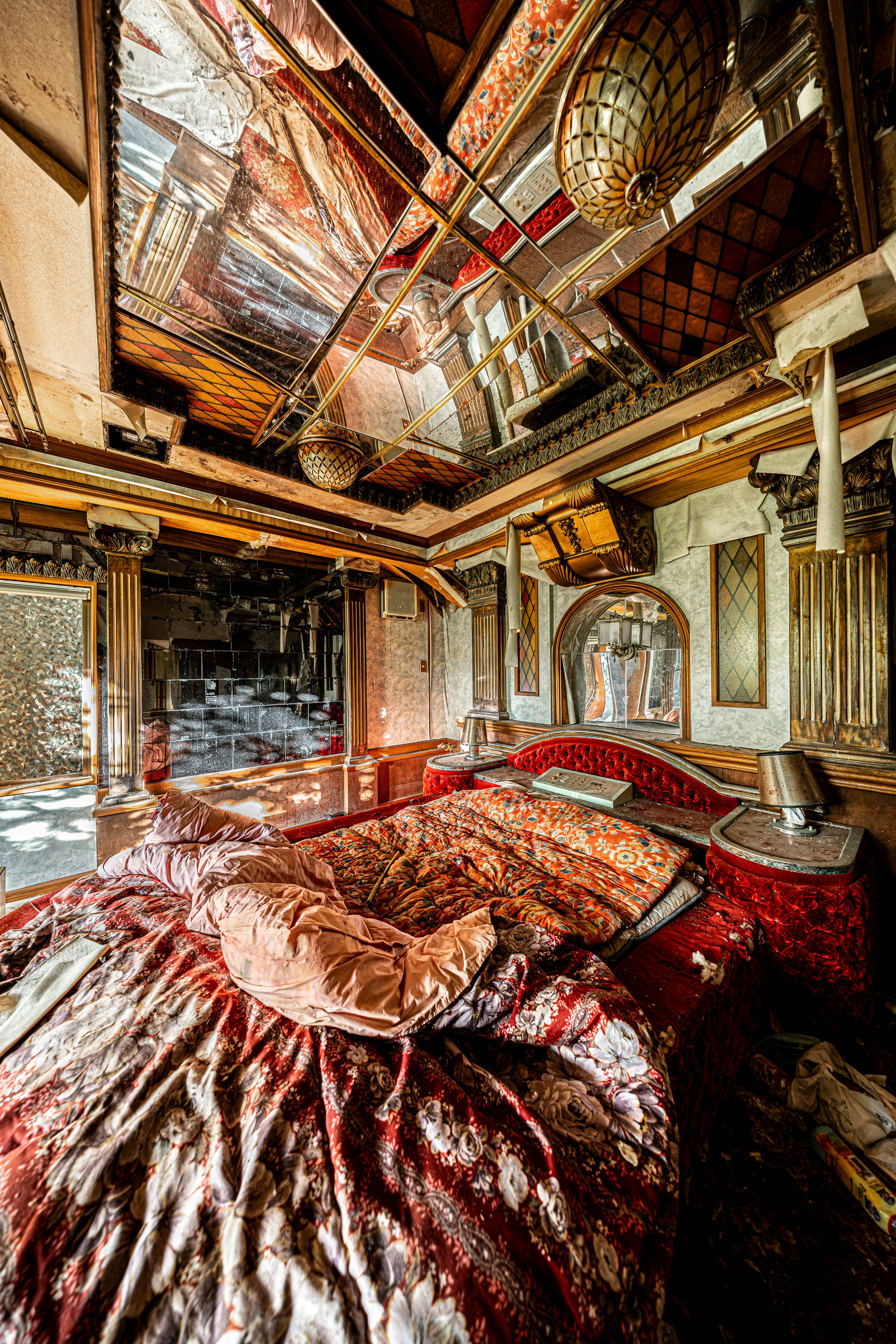 廃墟のような室内で赤いベッドと天井の梁が見える寝室