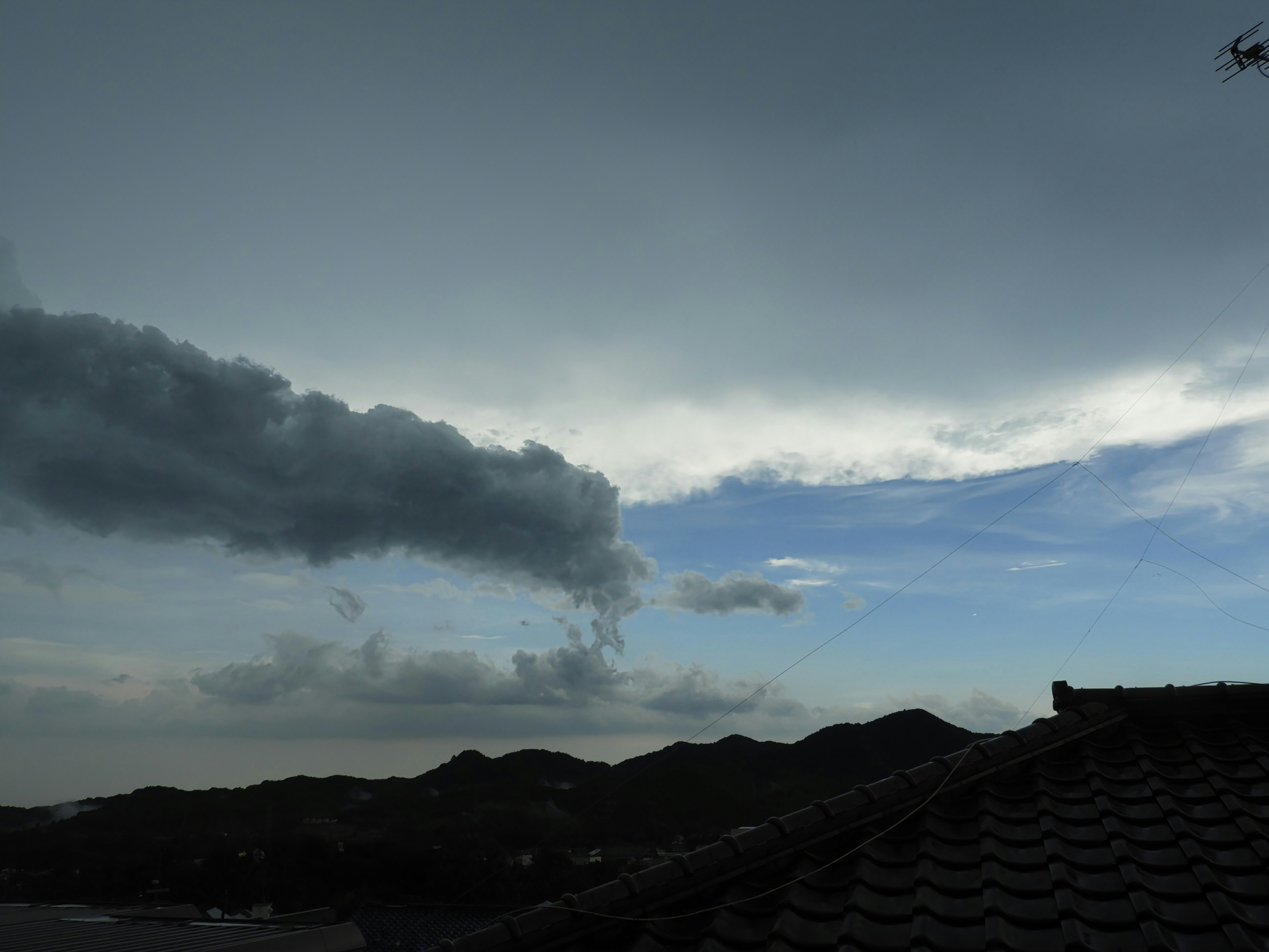 雨雲の下で山並みと雲が広がる風景