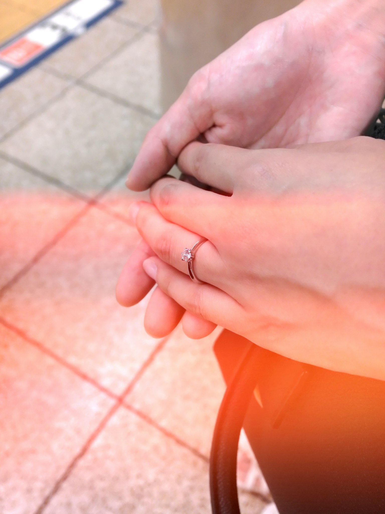 Primer plano de dos manos entrelazadas con un anillo en un dedo