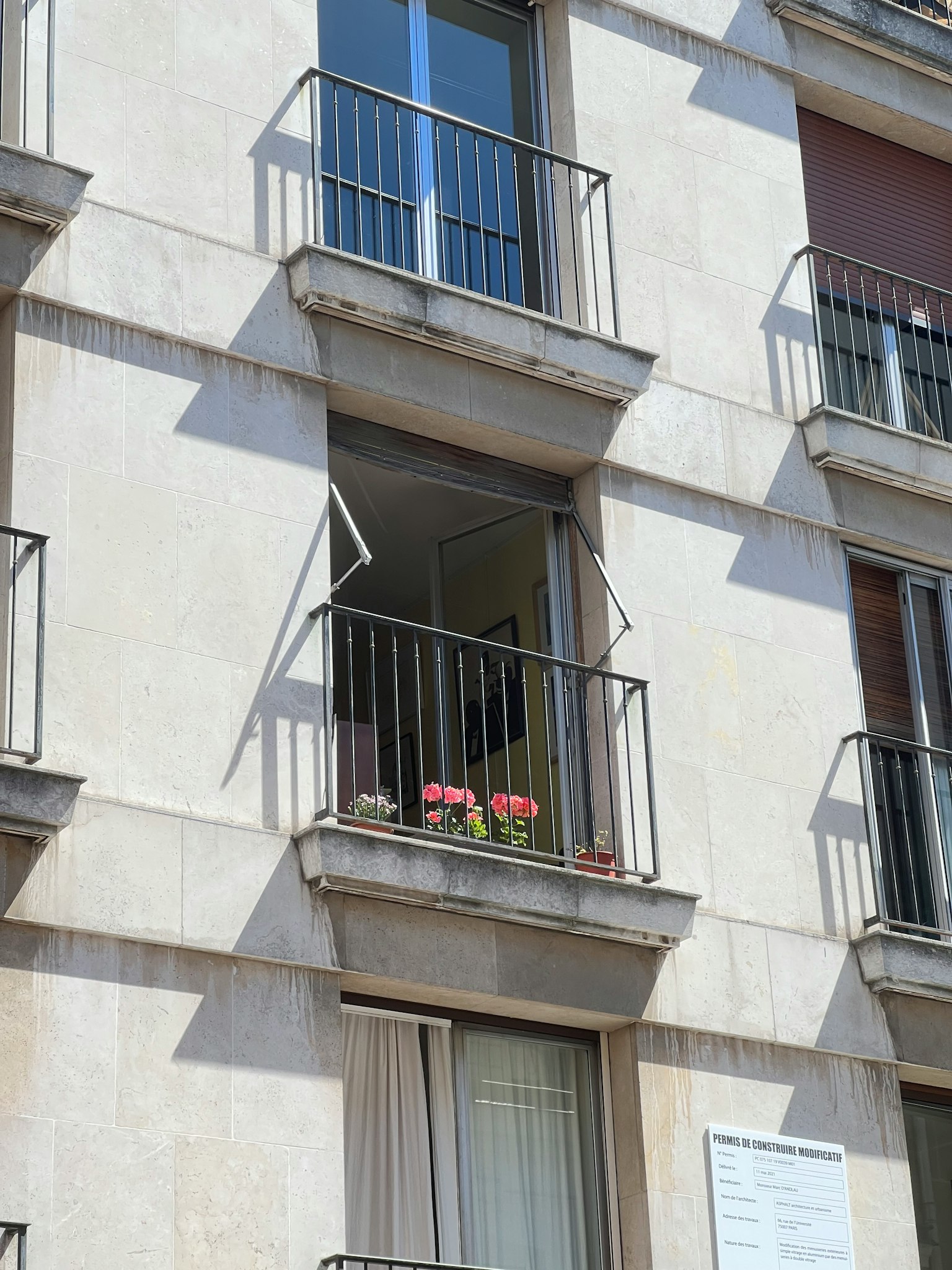 Vue extérieure d'un bâtiment blanc avec un balcon orné de fleurs