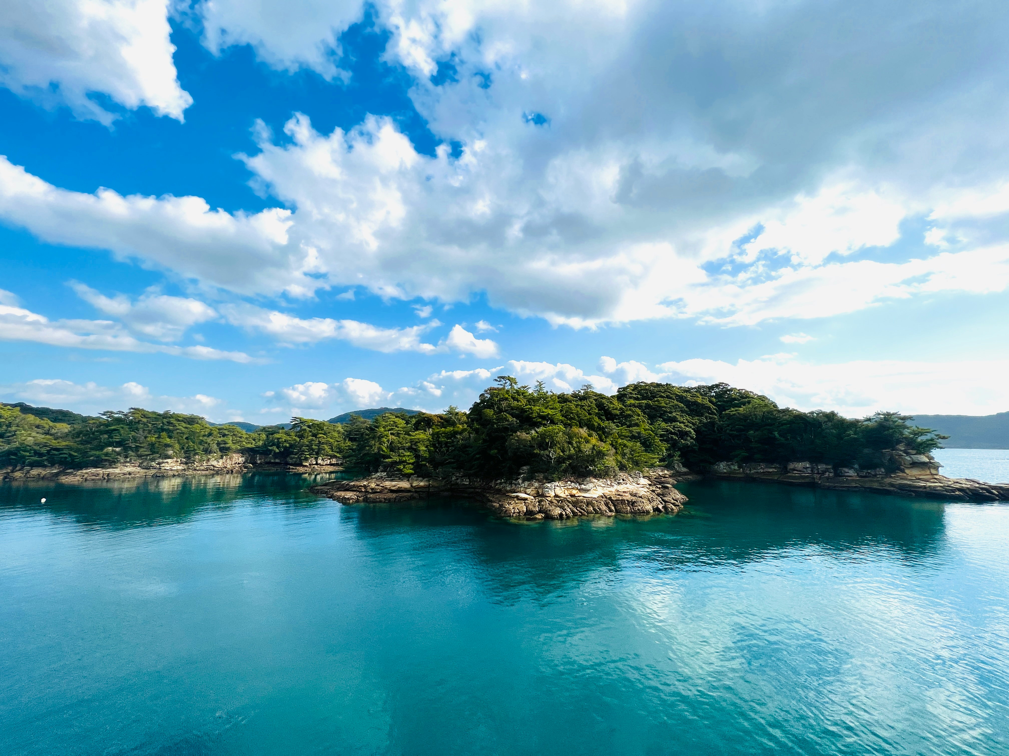 Teluk tenang dengan pulau hijau dan air yang tenang