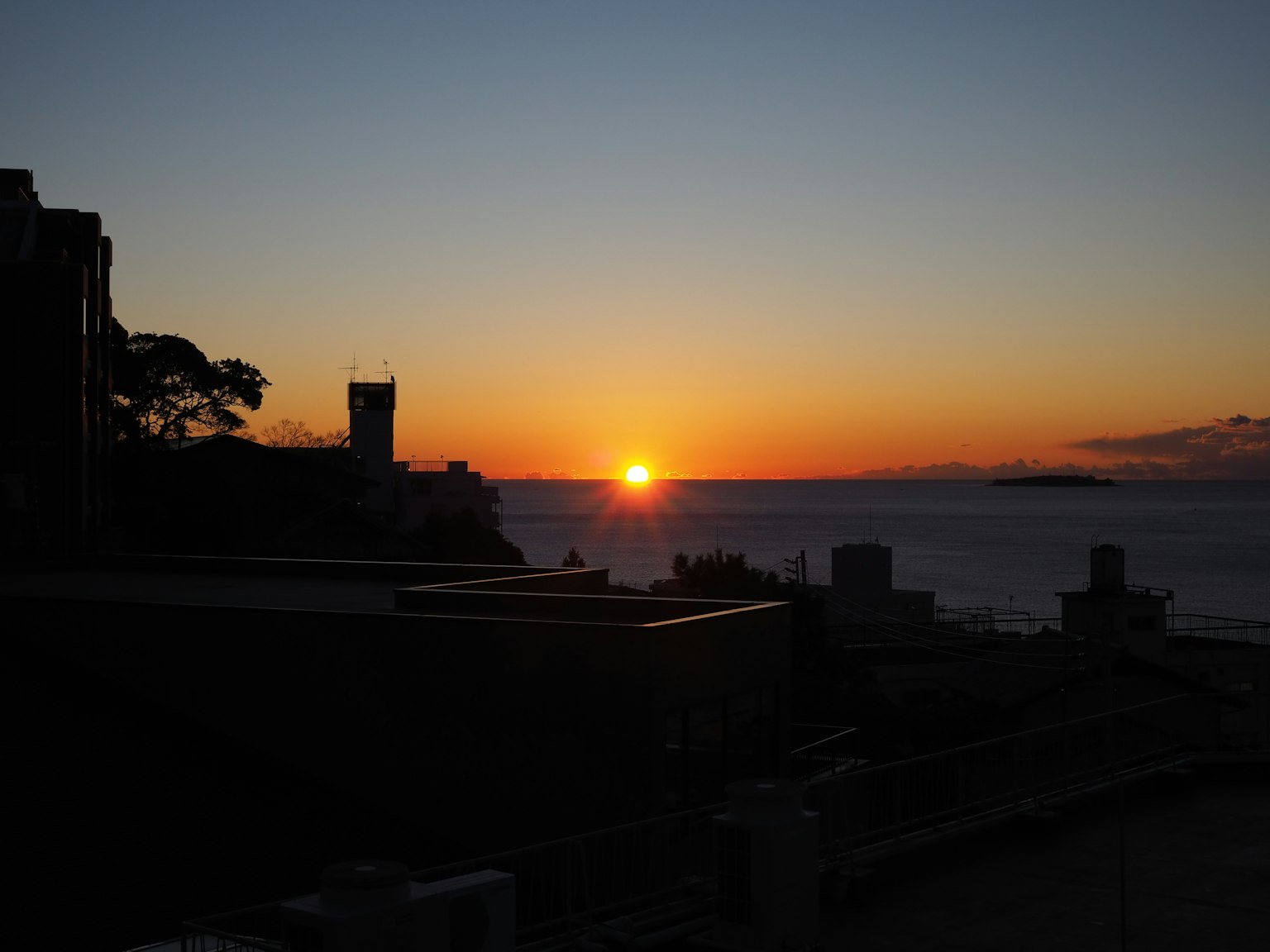 Bellissimo tramonto sull'oceano con edifici in silhouette e colori vivaci nel cielo