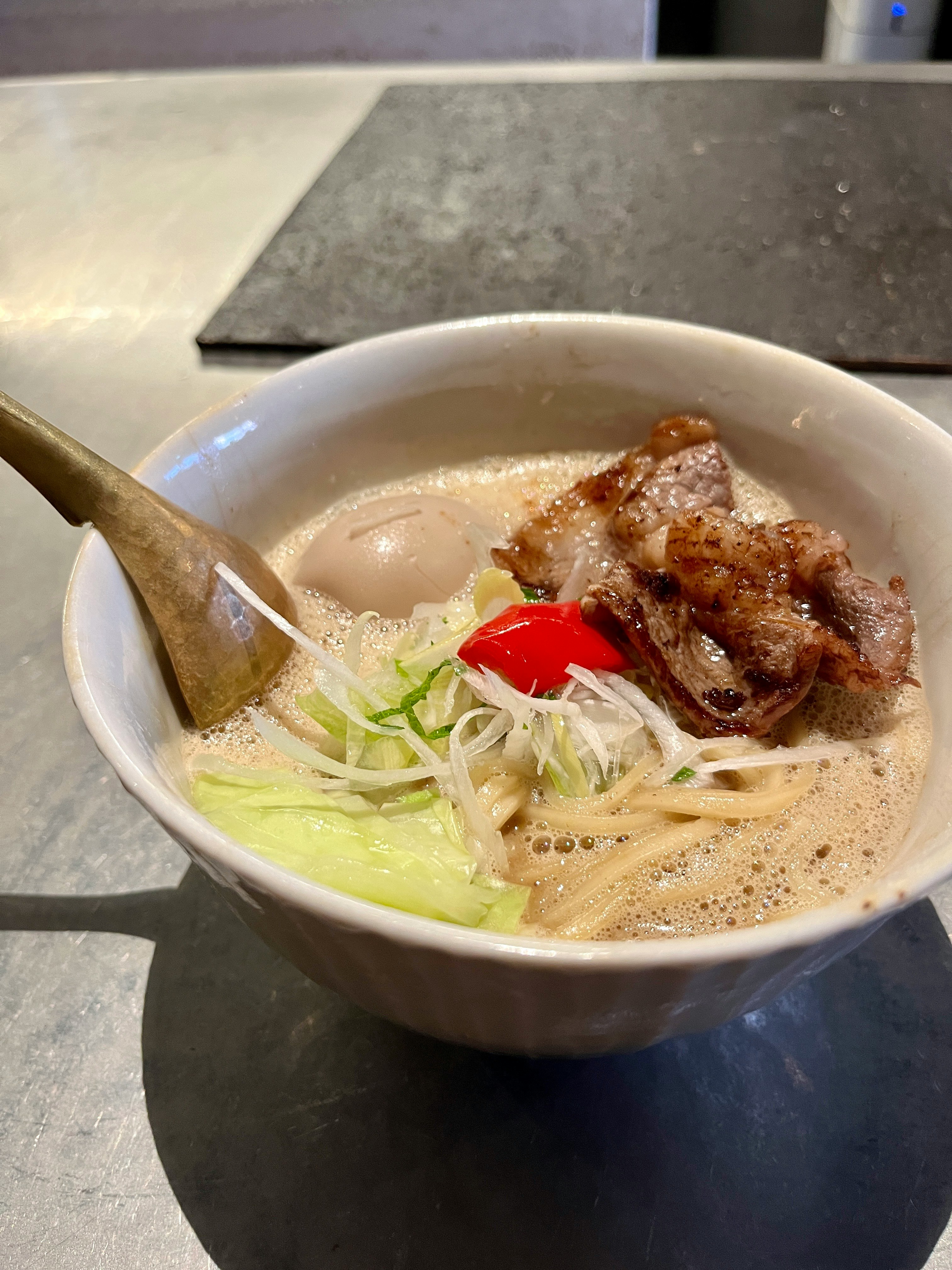 豚骨風ラーメンの器にチャーシューとネギ、味玉