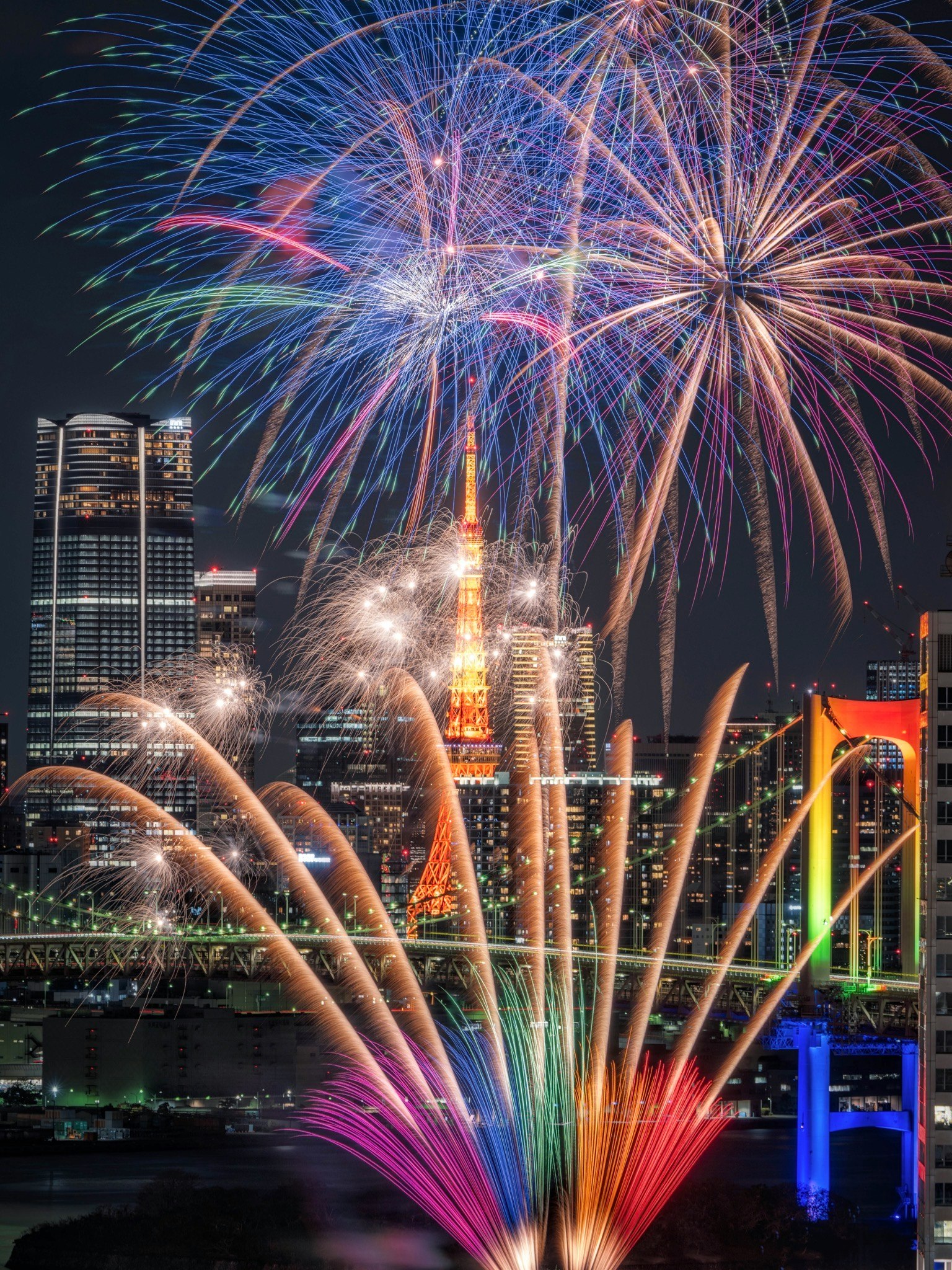 Spettacolo di fuochi d'artificio davanti alla Torre di Tokyo con il Ponte Rainbow di notte