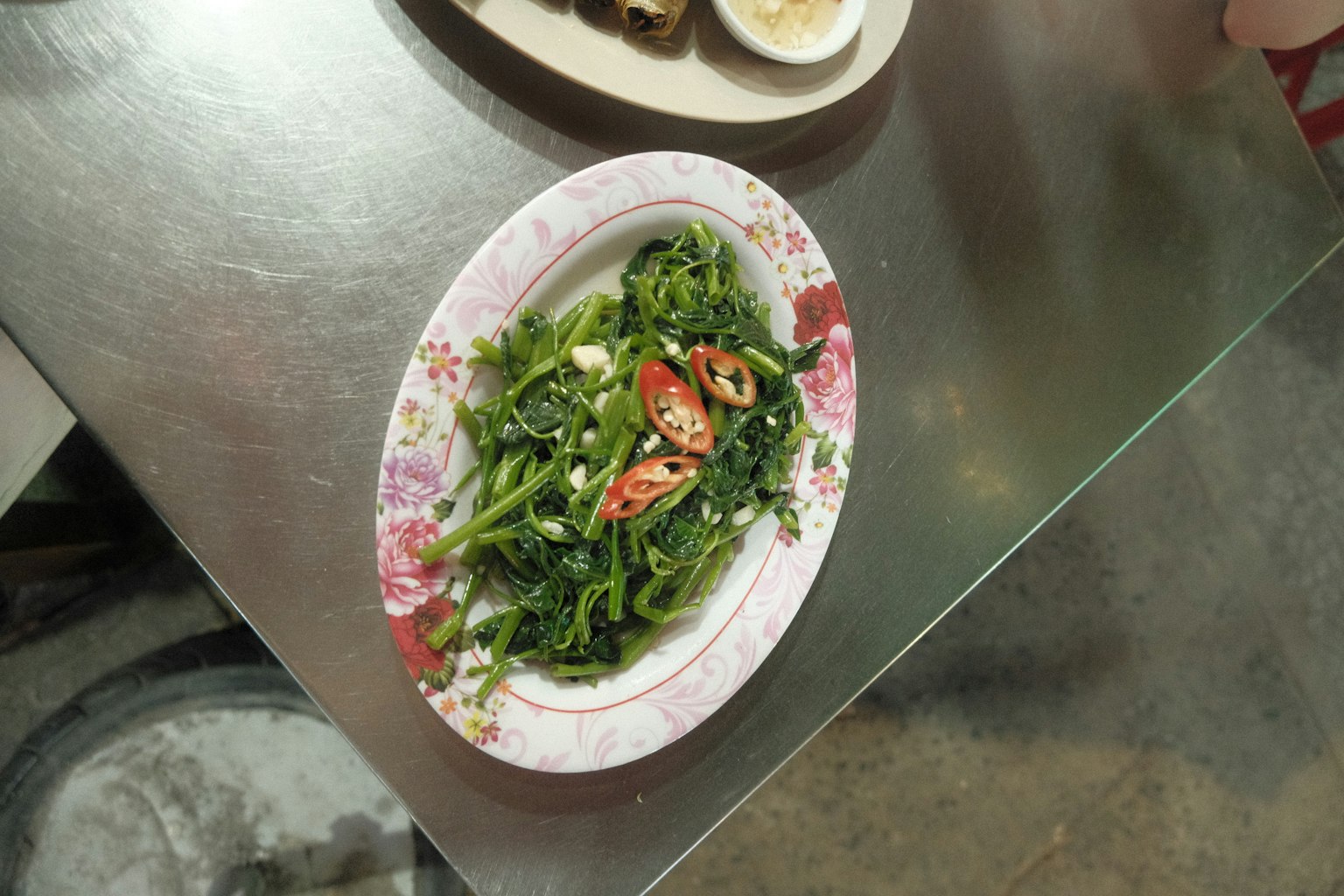 緑の野菜と赤い唐辛子が盛り付けられた皿